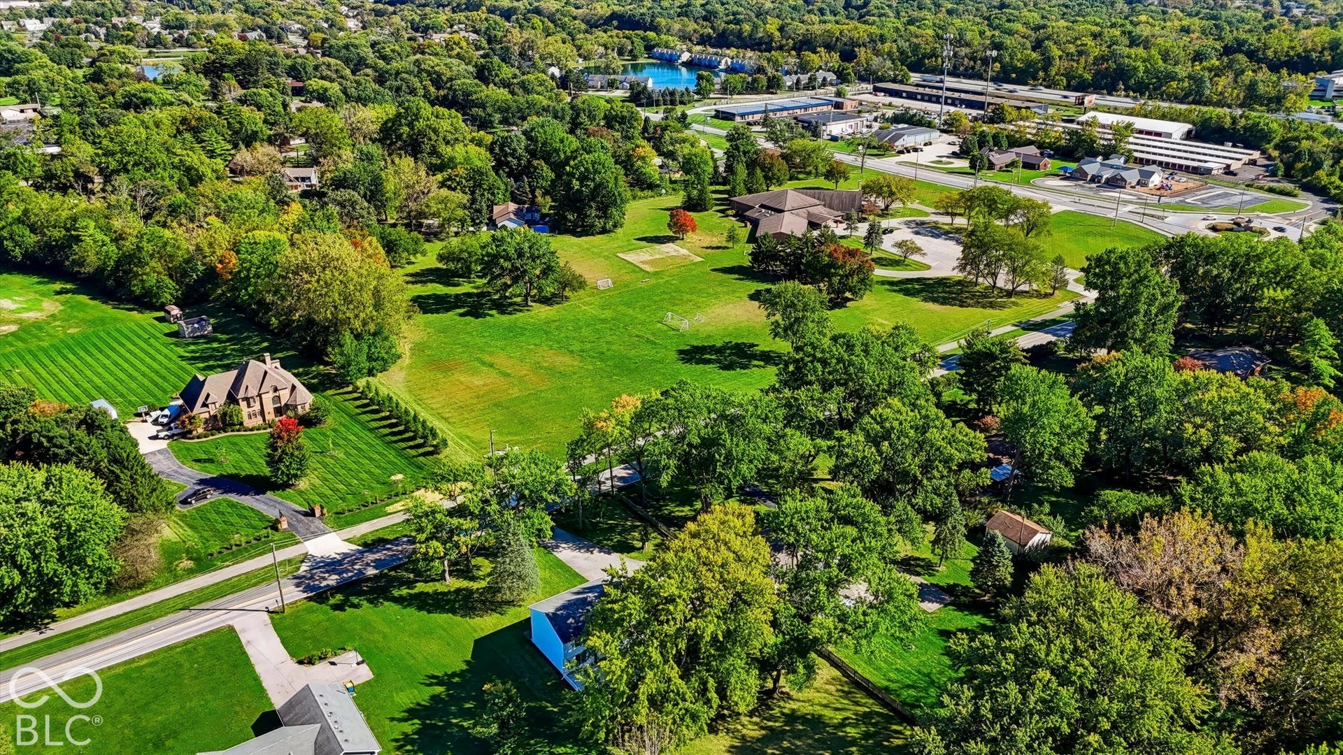 Expansive grounds featuring manicured lawns, mature specimen trees, and a sparkling blue water feature