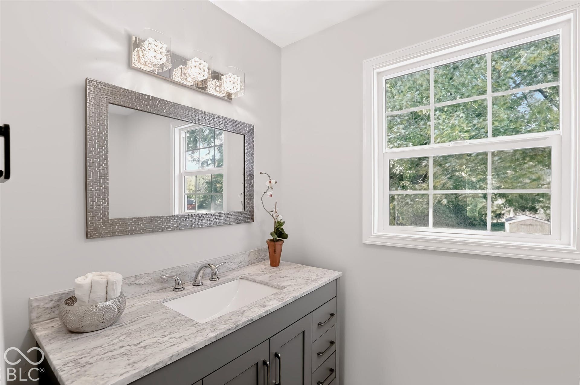 Spa-inspired bathroom vanity featuring a gray cabinetry base, marble-finish countertop, and polished nickel fixtures