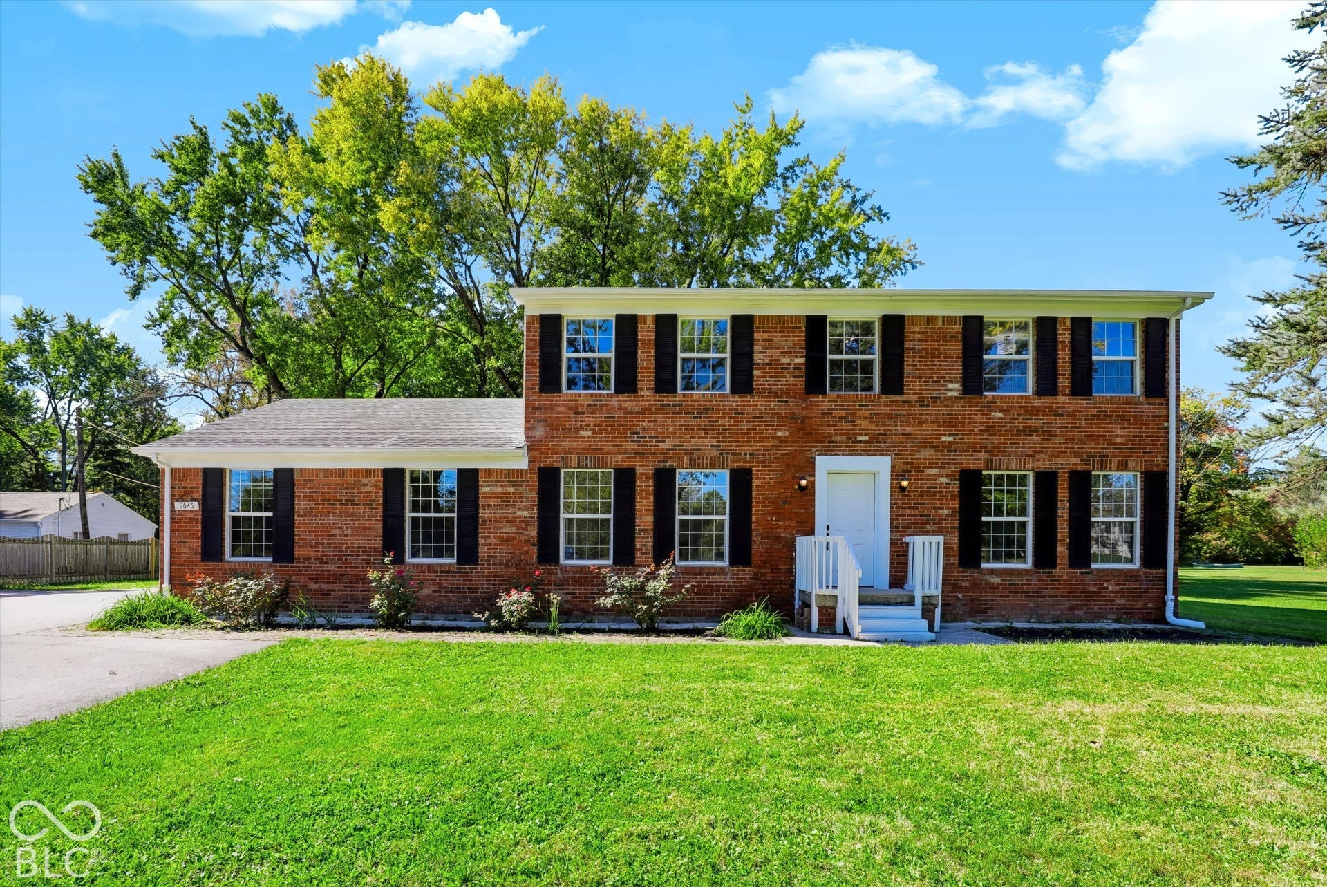 Classic all-brick Colonial featuring a symmetrical facade with blue-shuttered windows, a centered white entry door with portico, and a two-story design