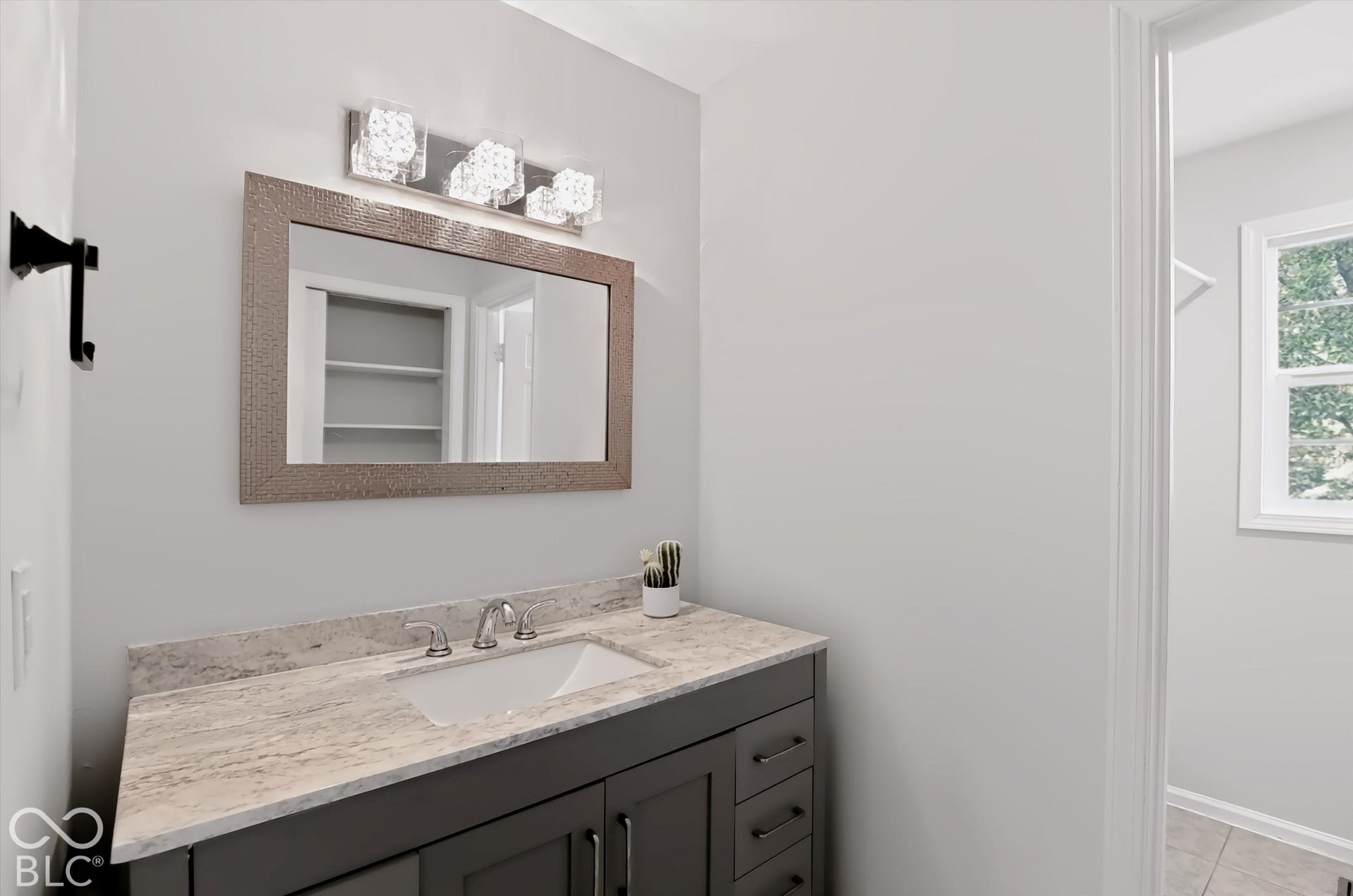 Vanity with a light-toned stone-look countertop, undermount sink, and chrome faucet
