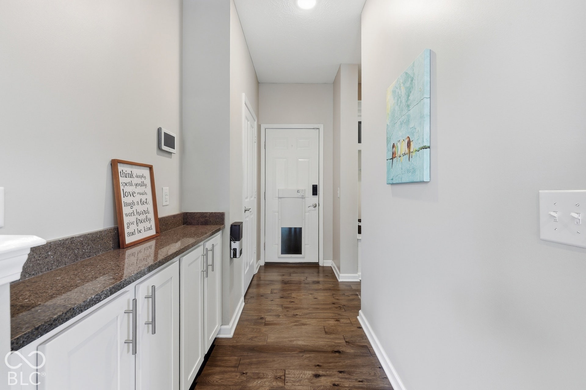 Wood-finish flooring leading to a built-in cabinet system with a stone-finish countertop