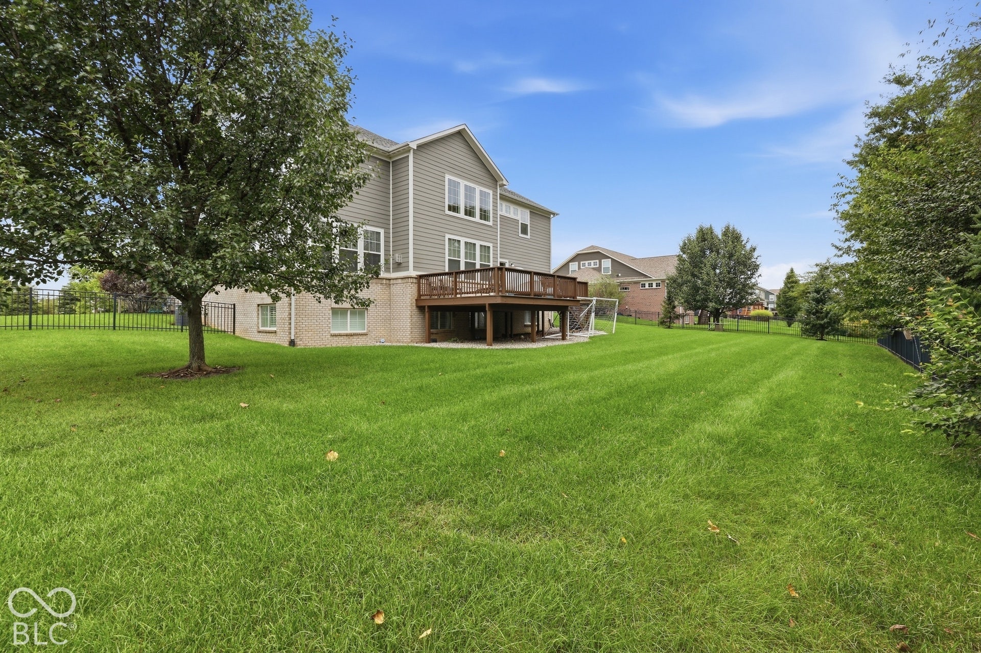 Expansive green lawn with mature trees and a fenced perimeter