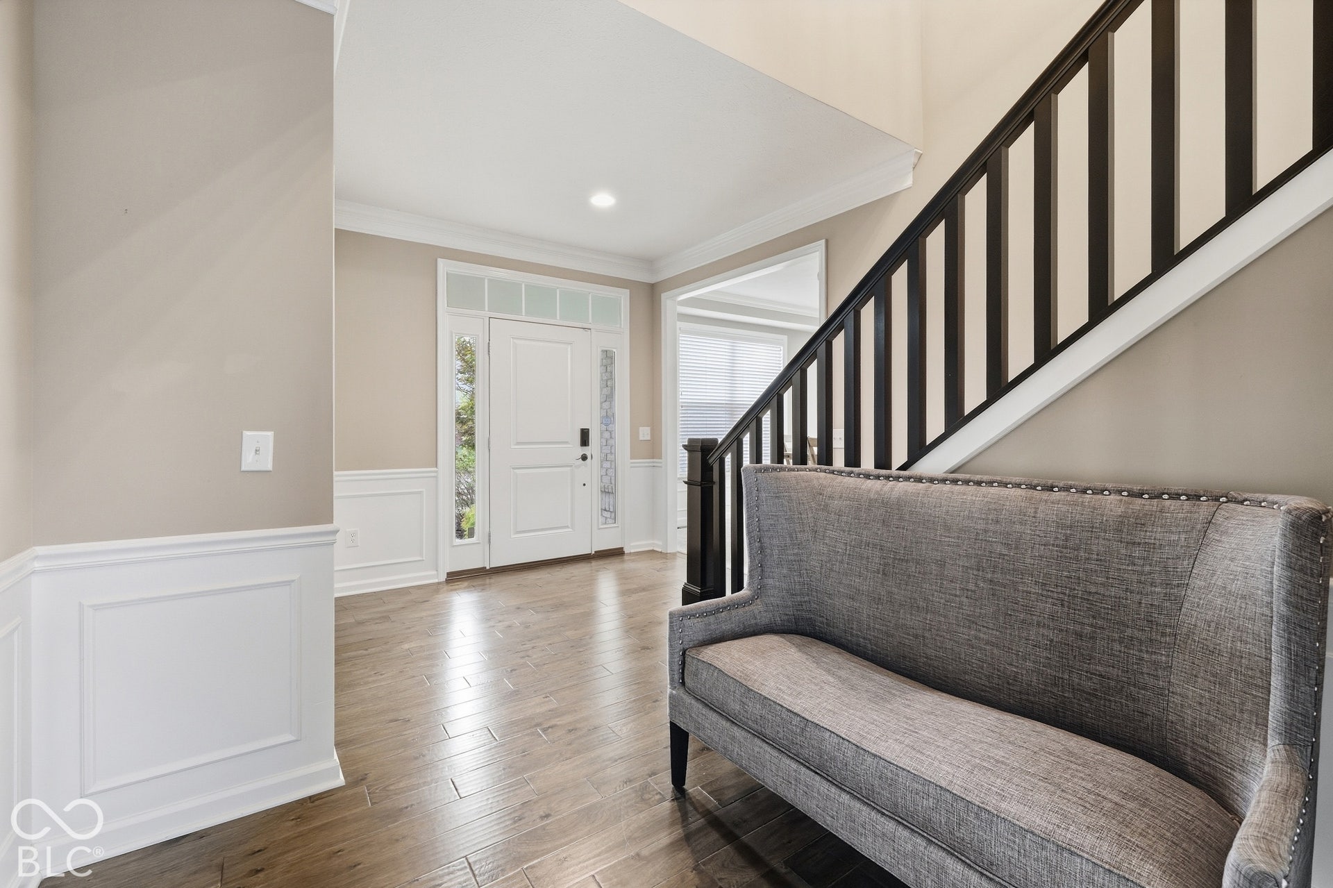 Entryway featuring wood-finish flooring, wainscoting, and a white paneled door with sidelights