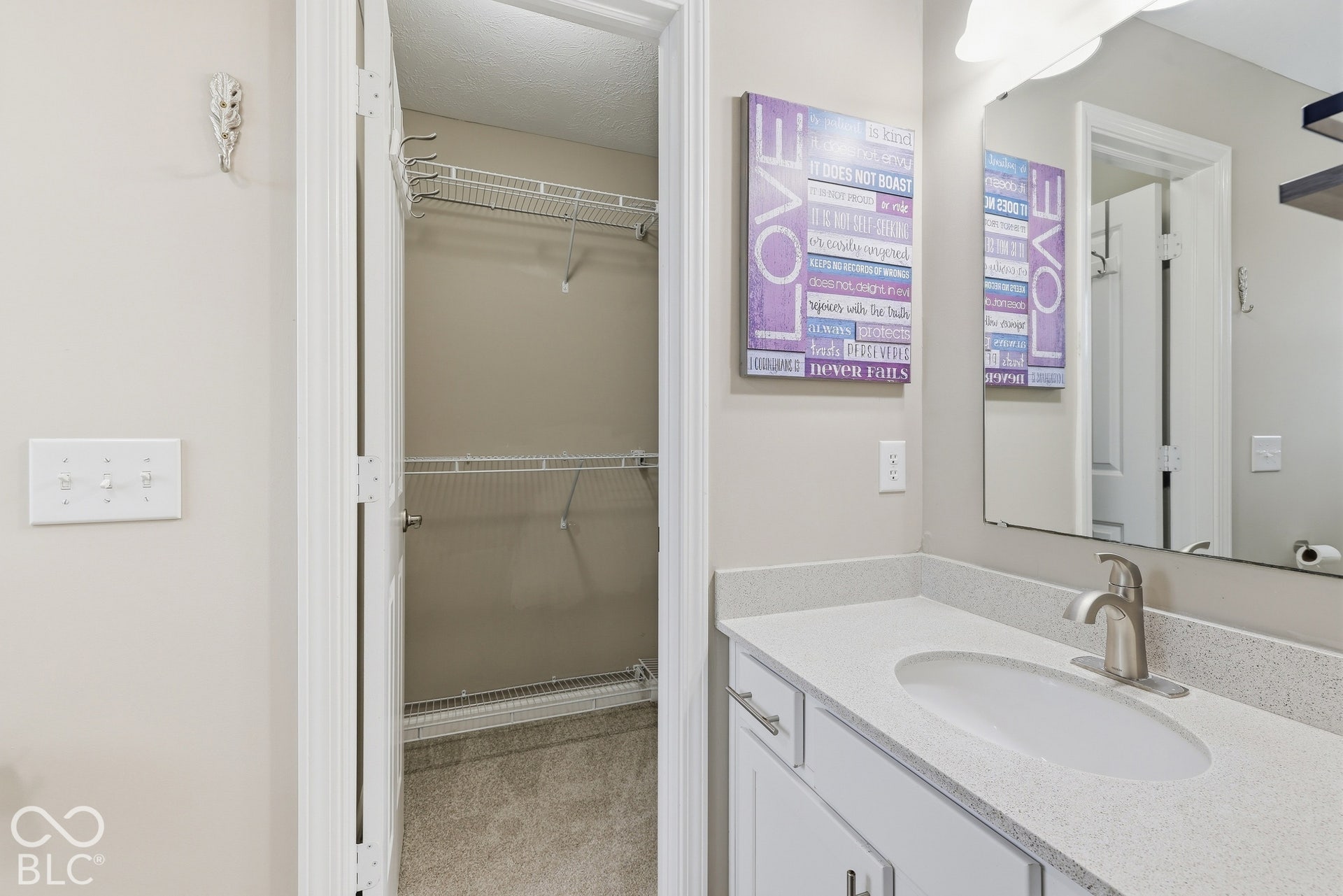 Private bath bedroom 5 with walk-in closet, single vanity with an integrated sink, brushed nickel faucet, and a large mirror