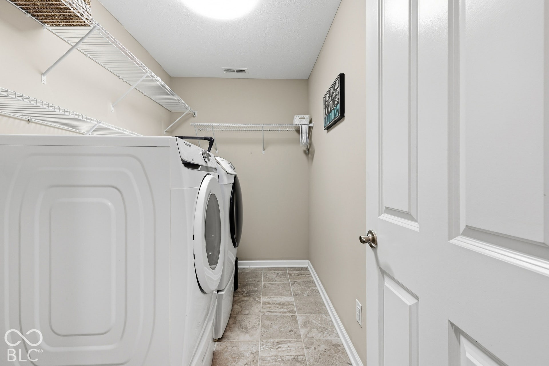 Upstairs laundry room featuring tile flooring, shelving, and a panel door