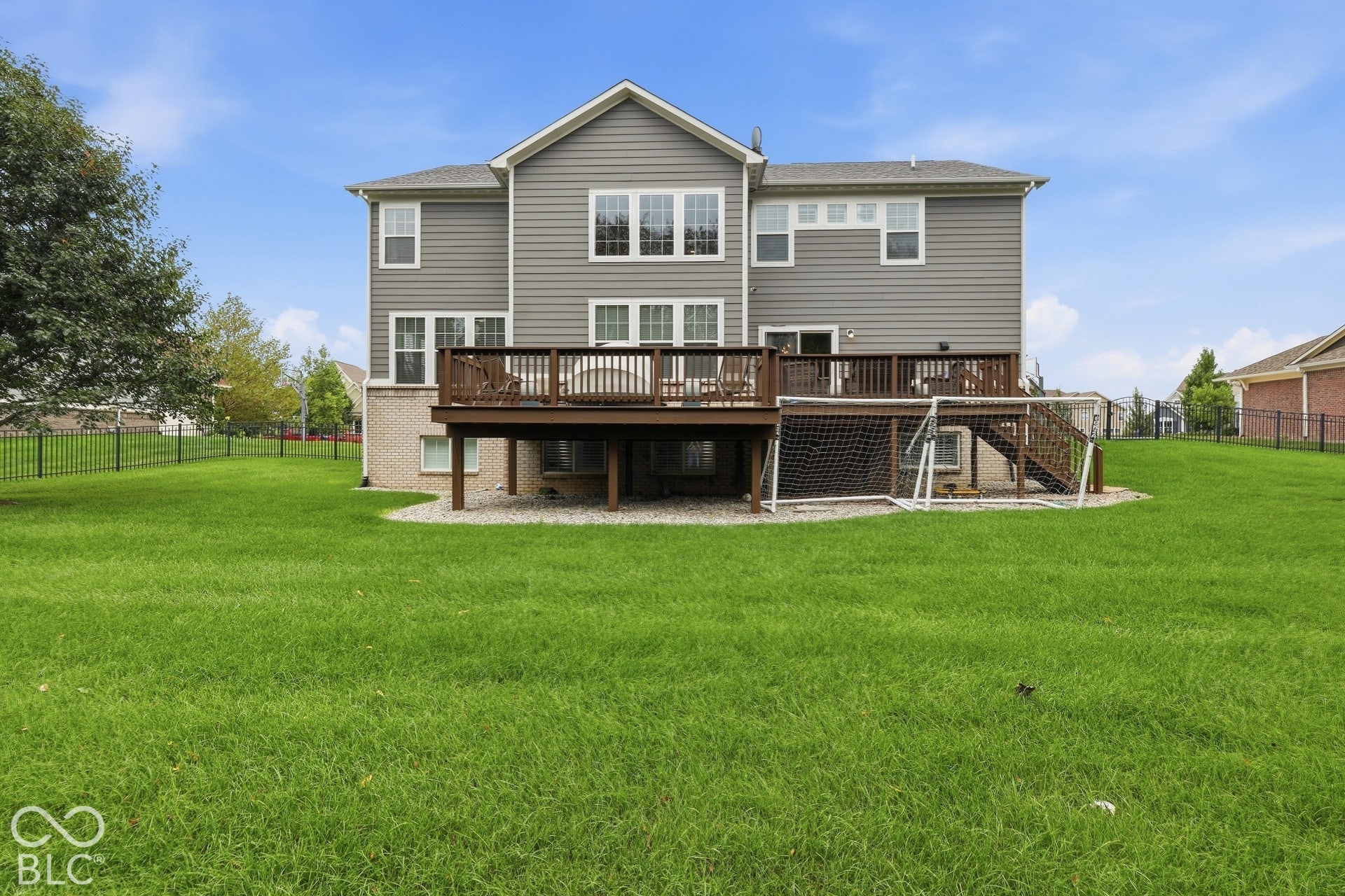 Expansive grassy yard with a multi-level wood deck, fenced yard with sprinkler system