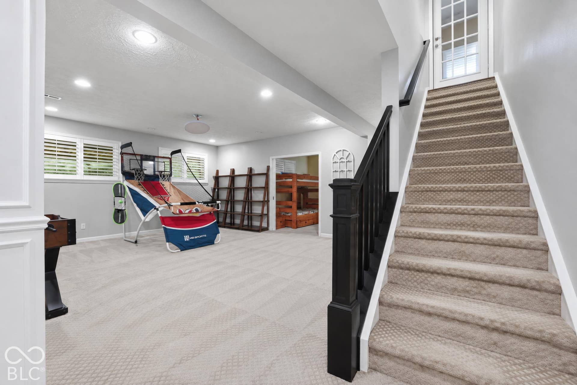 Carpeted staircase with dark wood newel post and handrail, leading to a white door with glass panels