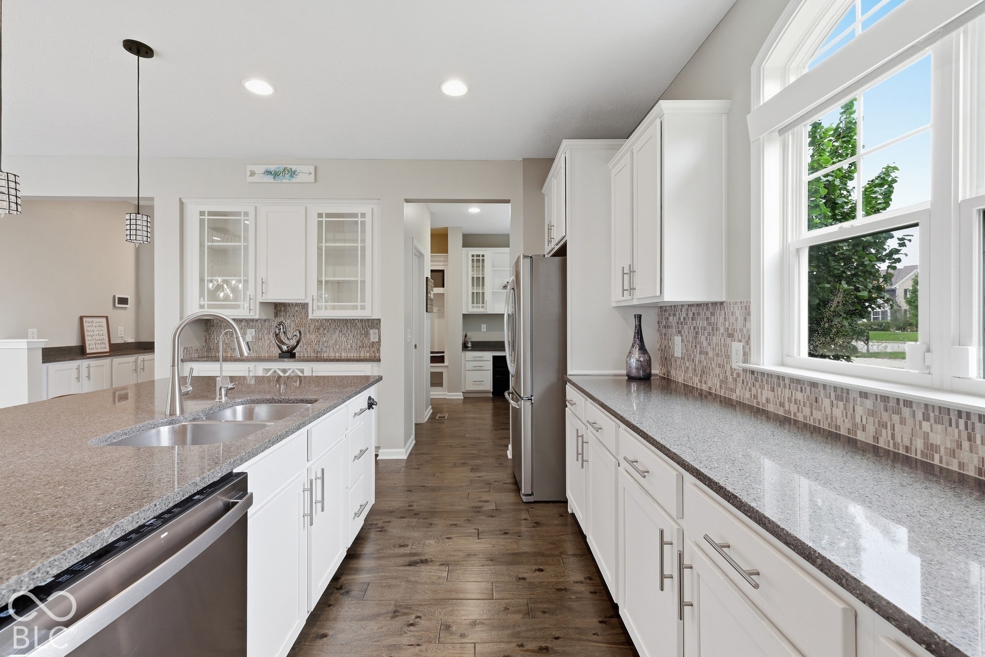 Kitchen featuring white cabinetry, stone countertops, stainless steel appliances, and wood-finish flooring