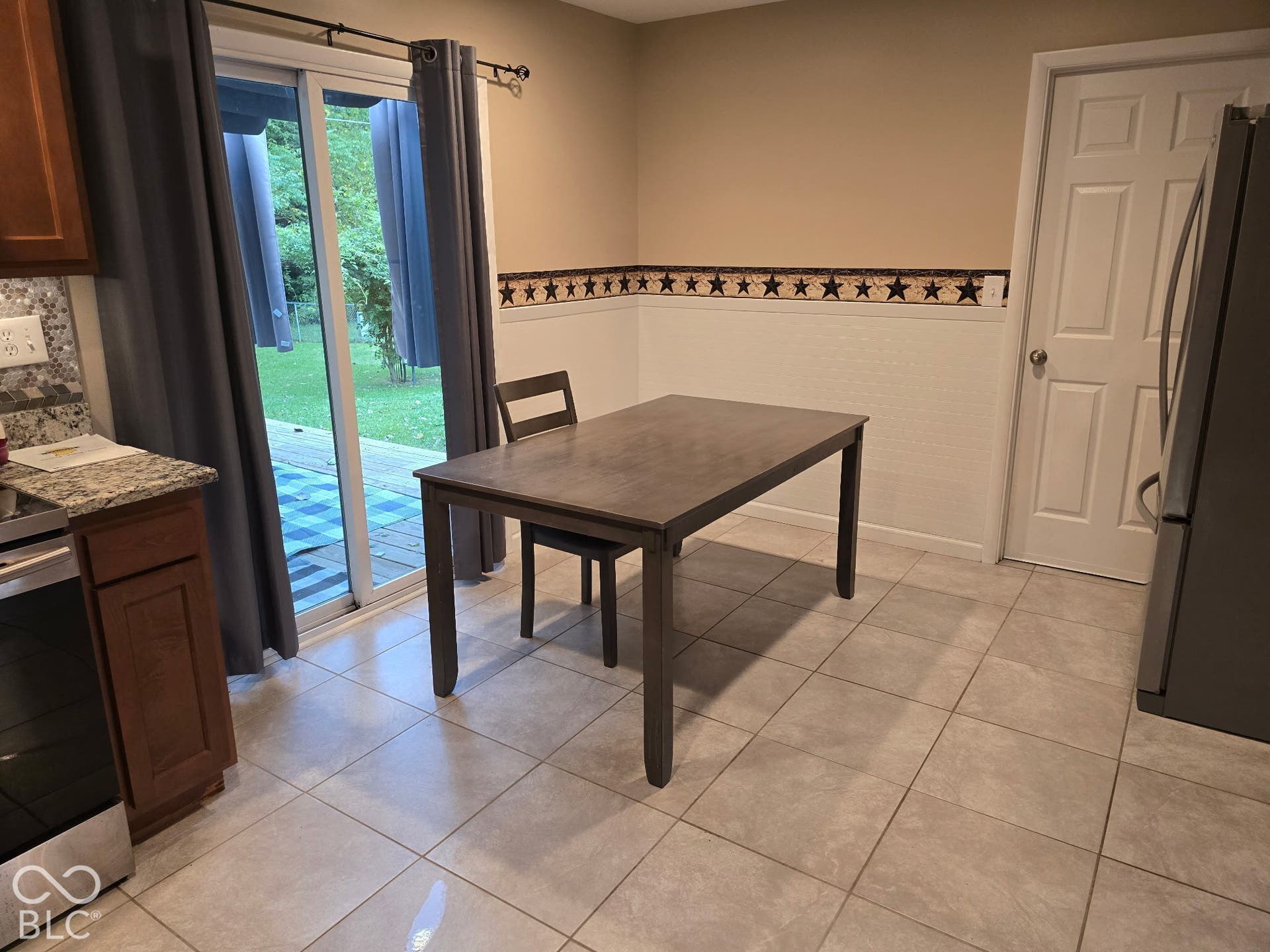 Sliding glass door, tiled flooring, wood-finish cabinetry, granite-style countertop, stainless steel refrigerator