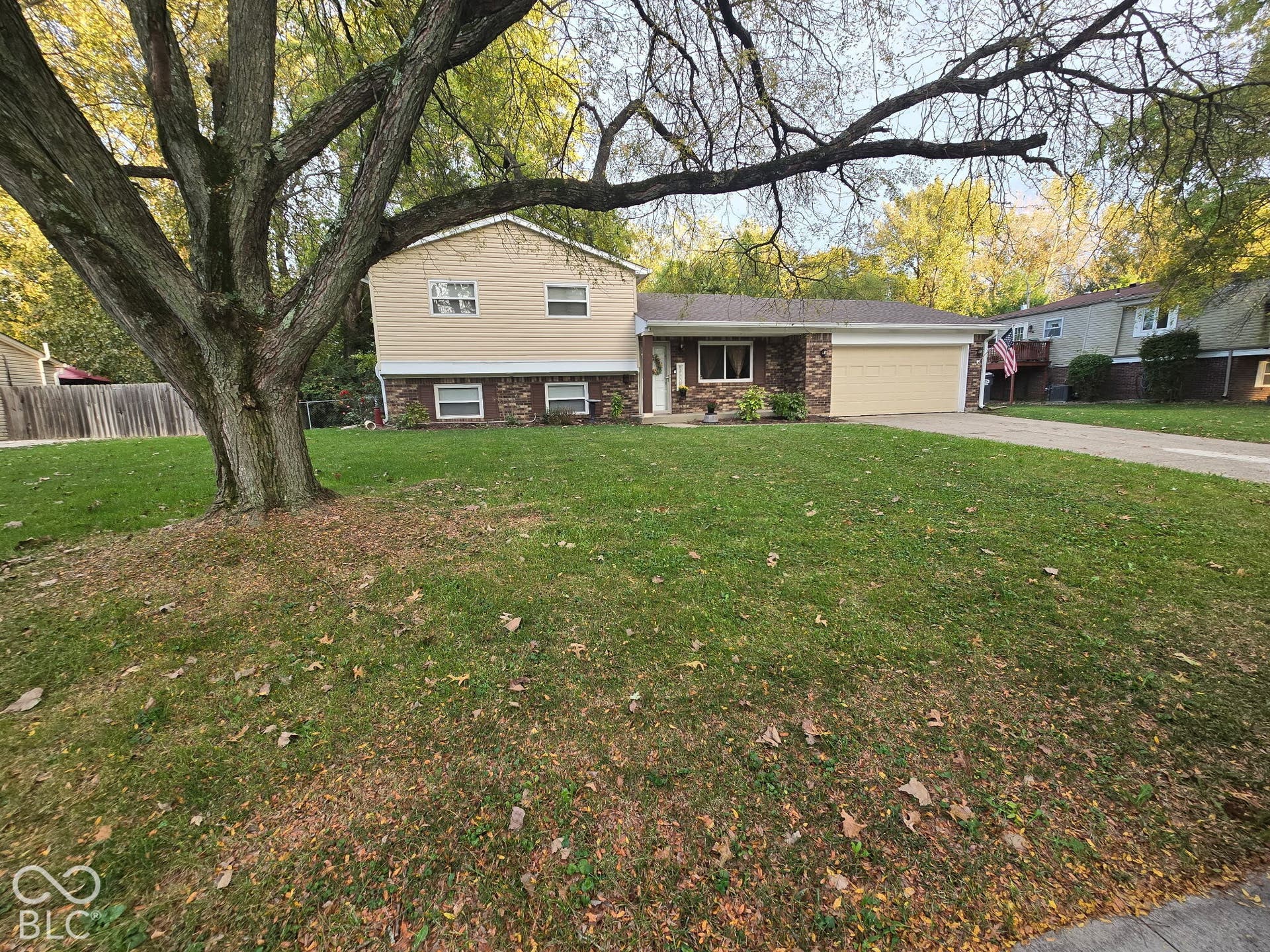 Split-level residence featuring a two-car garage, stone and siding exterior, and a concrete driveway