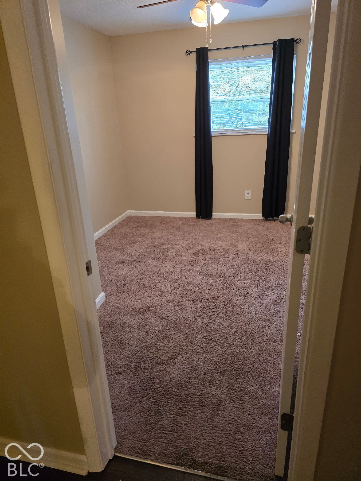 Room featuring plush carpet, neutral wall color, window with privacy coverings, and a ceiling fan
