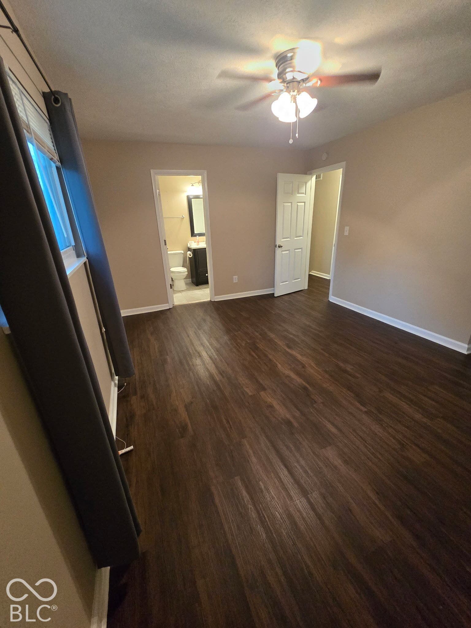 Wood-finish flooring throughout, ceiling fan with light fixture, and neutral wall tones