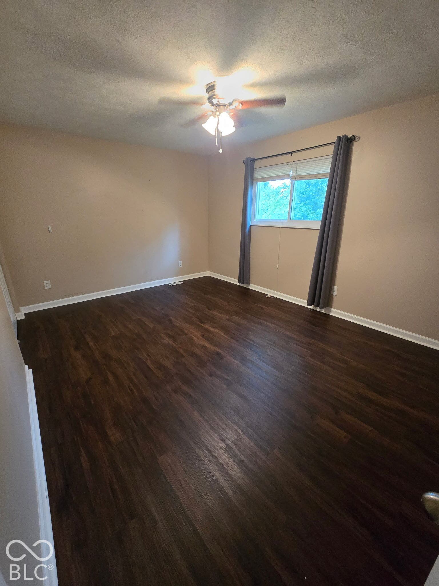 Wood-finish flooring with a ceiling fan light fixture and a single window