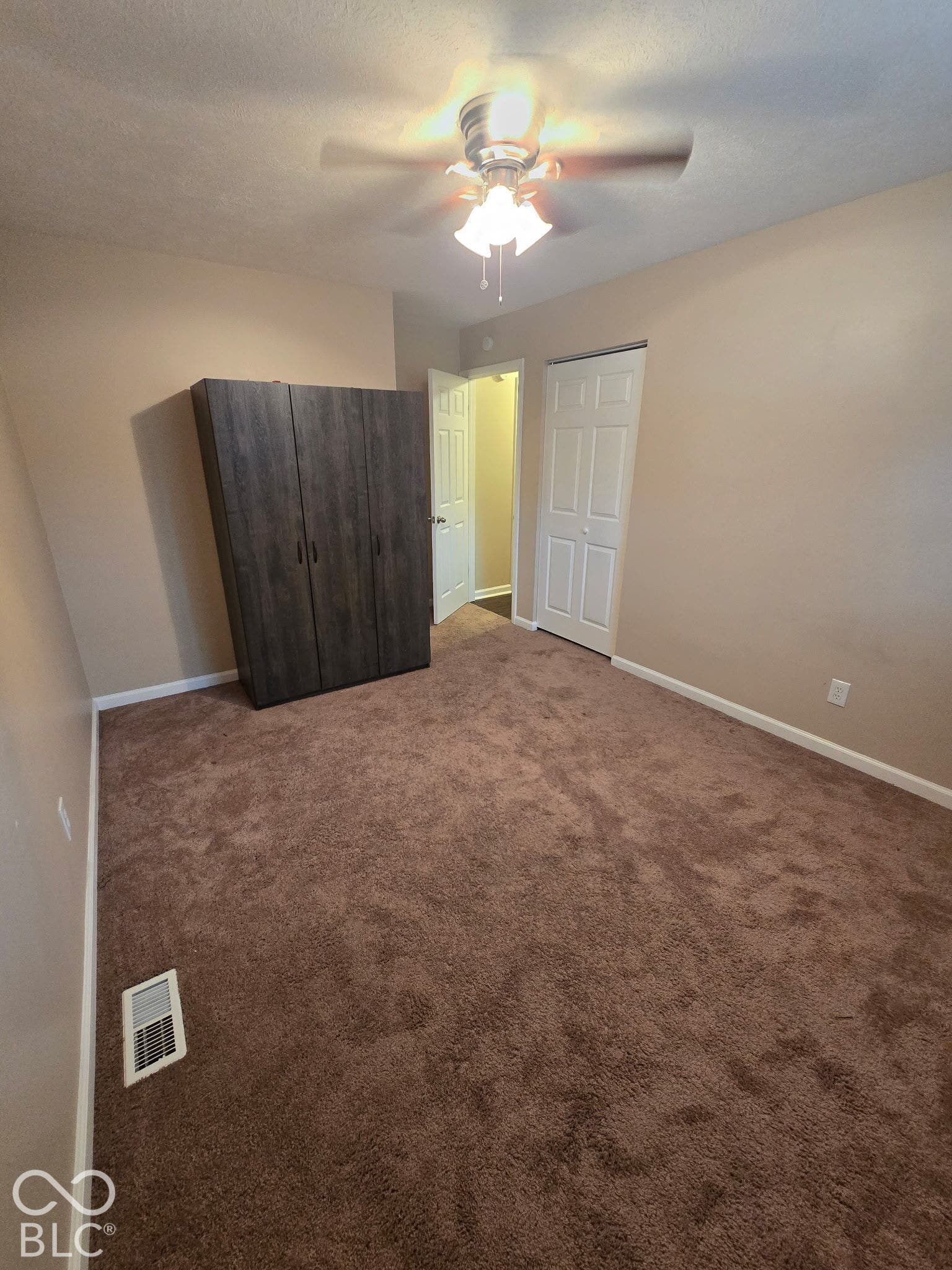 Wall-to-wall carpeting, neutral wall paint, and a ceiling fan with integrated lighting