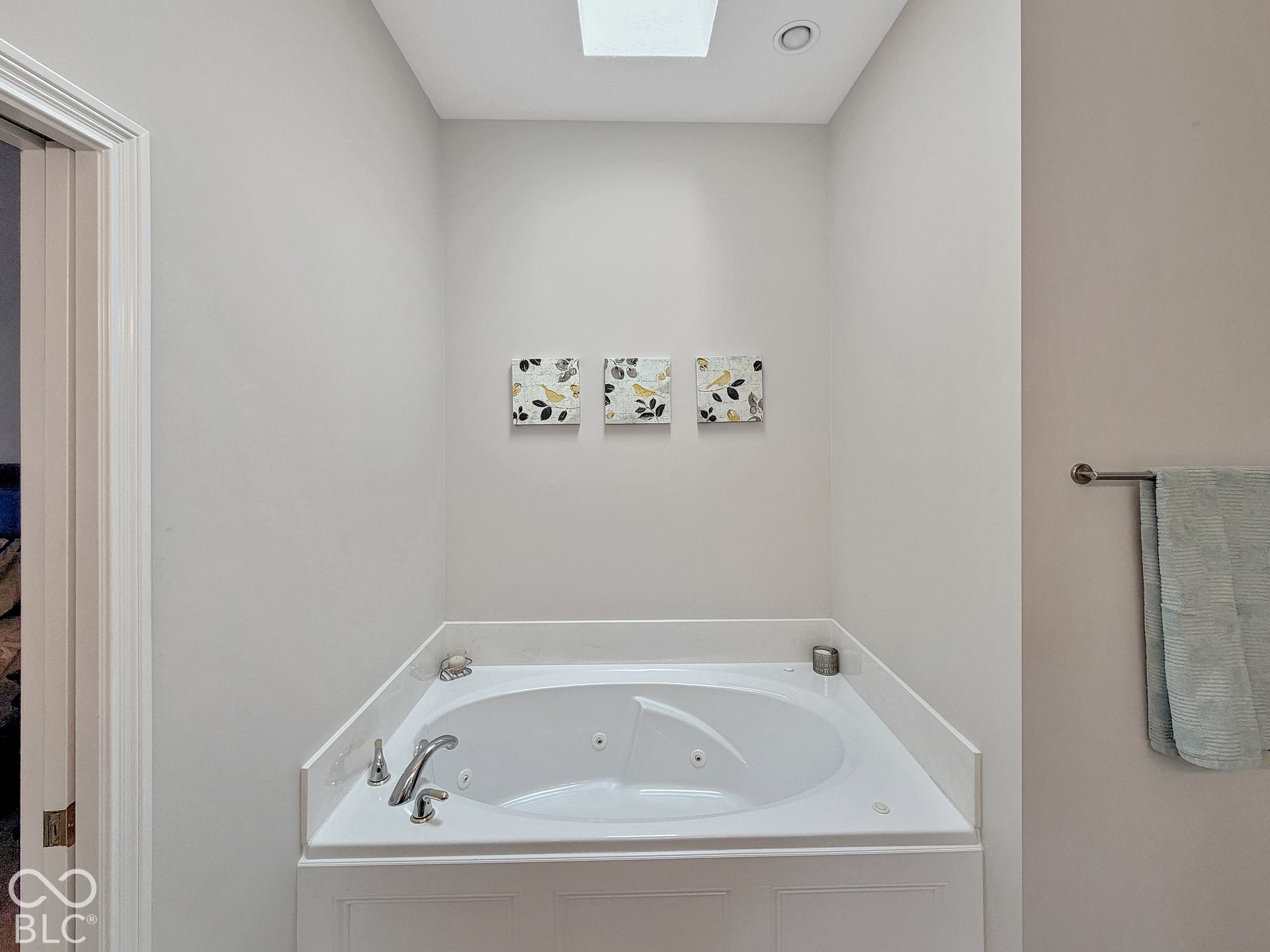 Built-in corner soaking tub with deck-mounted chrome fixtures, integrated jets, and a skylight overhead