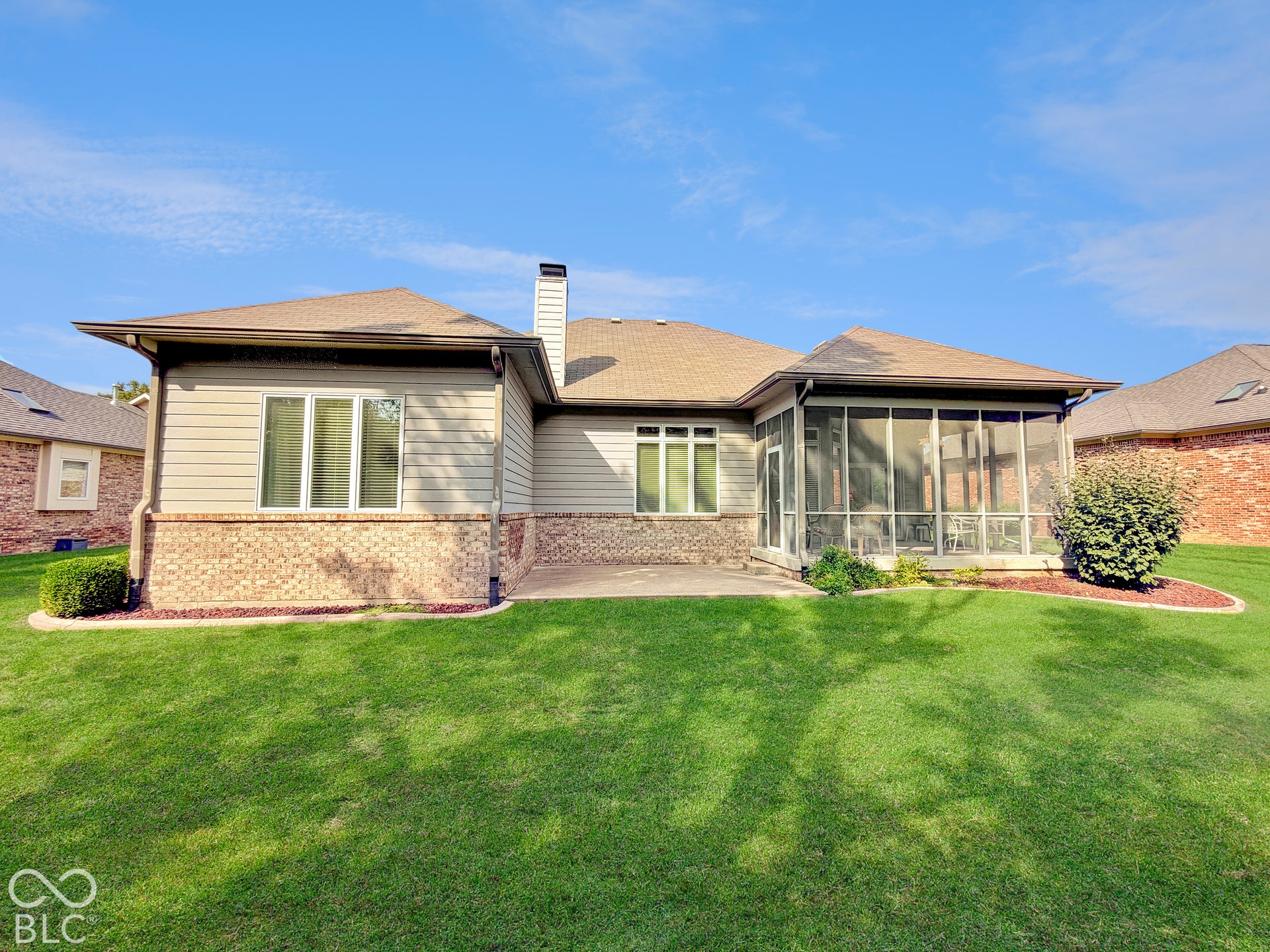 Expansive rear exterior featuring a screened-in porch, brick accents, and a concrete patio