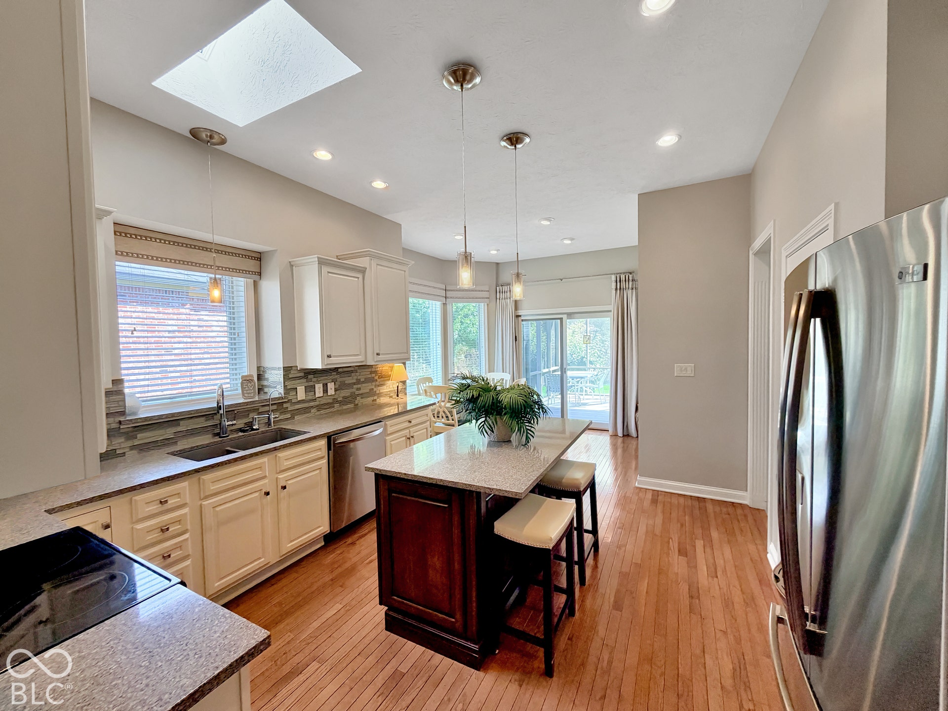 Kitchen featuring a skylight, recessed lighting, wood-finish flooring, a central island with countertop seating, and stainless steel appliances