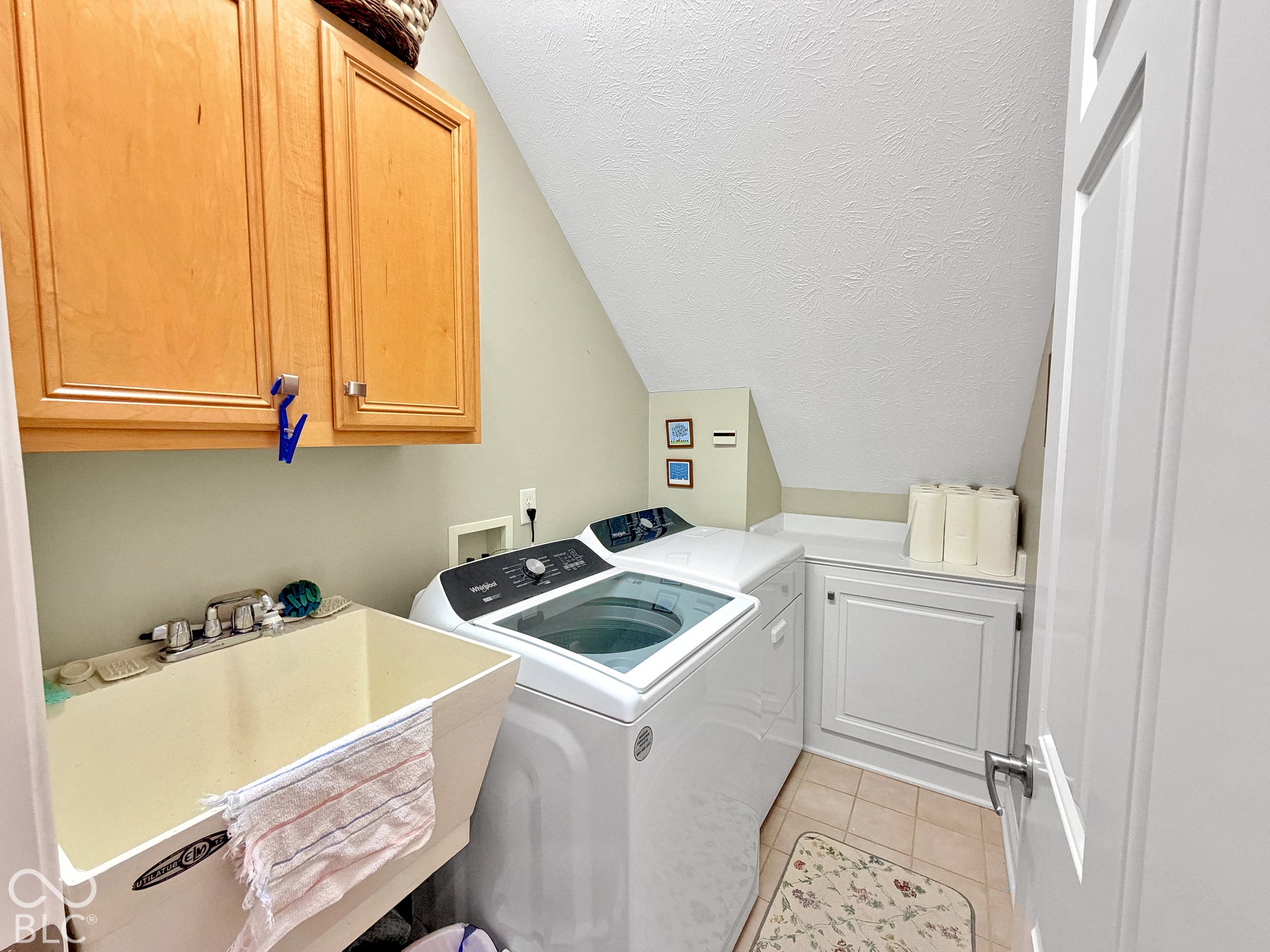 Laundry area featuring wood-finish cabinetry, a utility sink, and built-in storage