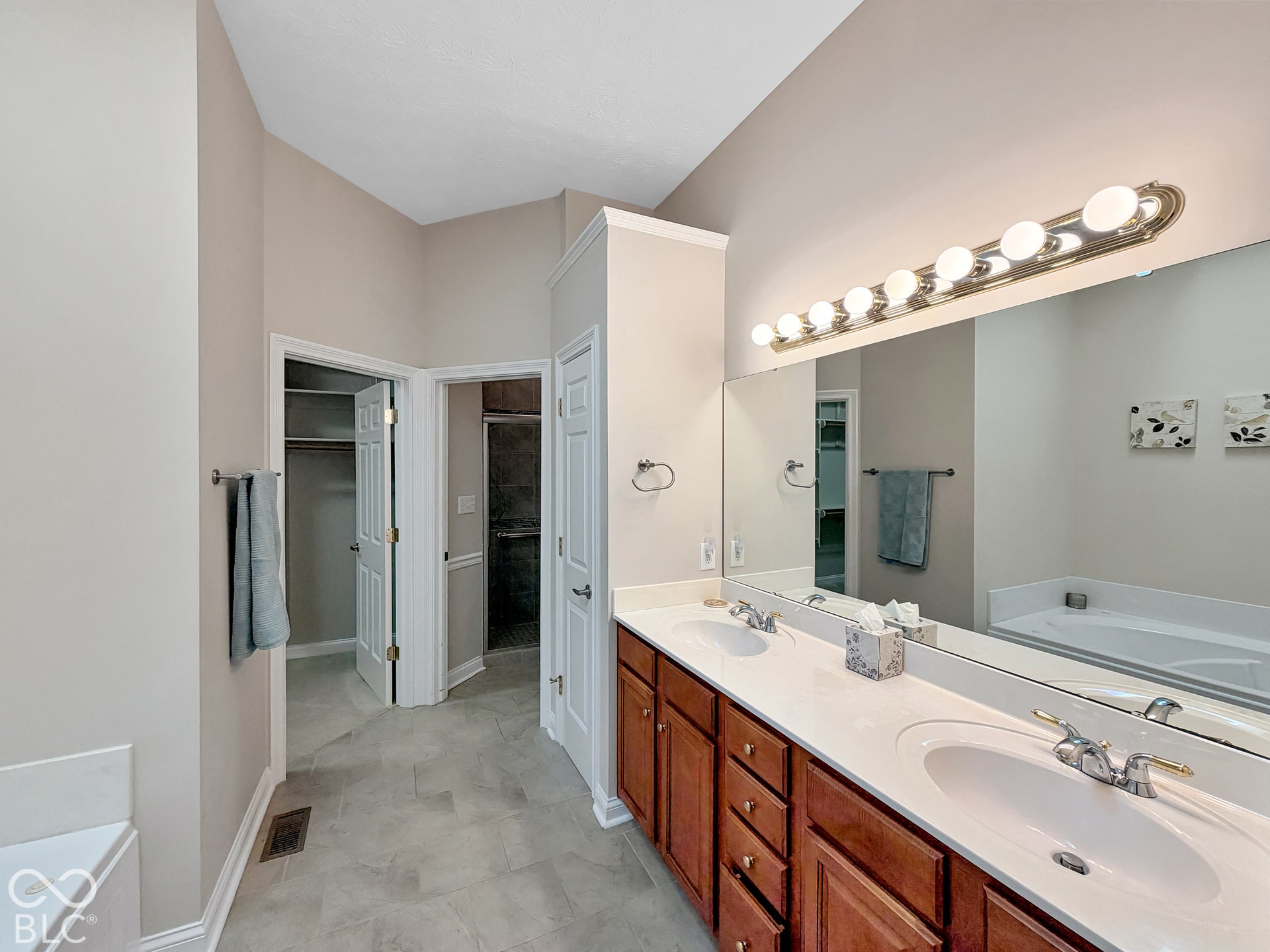 Bathroom featuring a dual vanity with a white countertop, large wall-mounted mirror, and tile flooring
