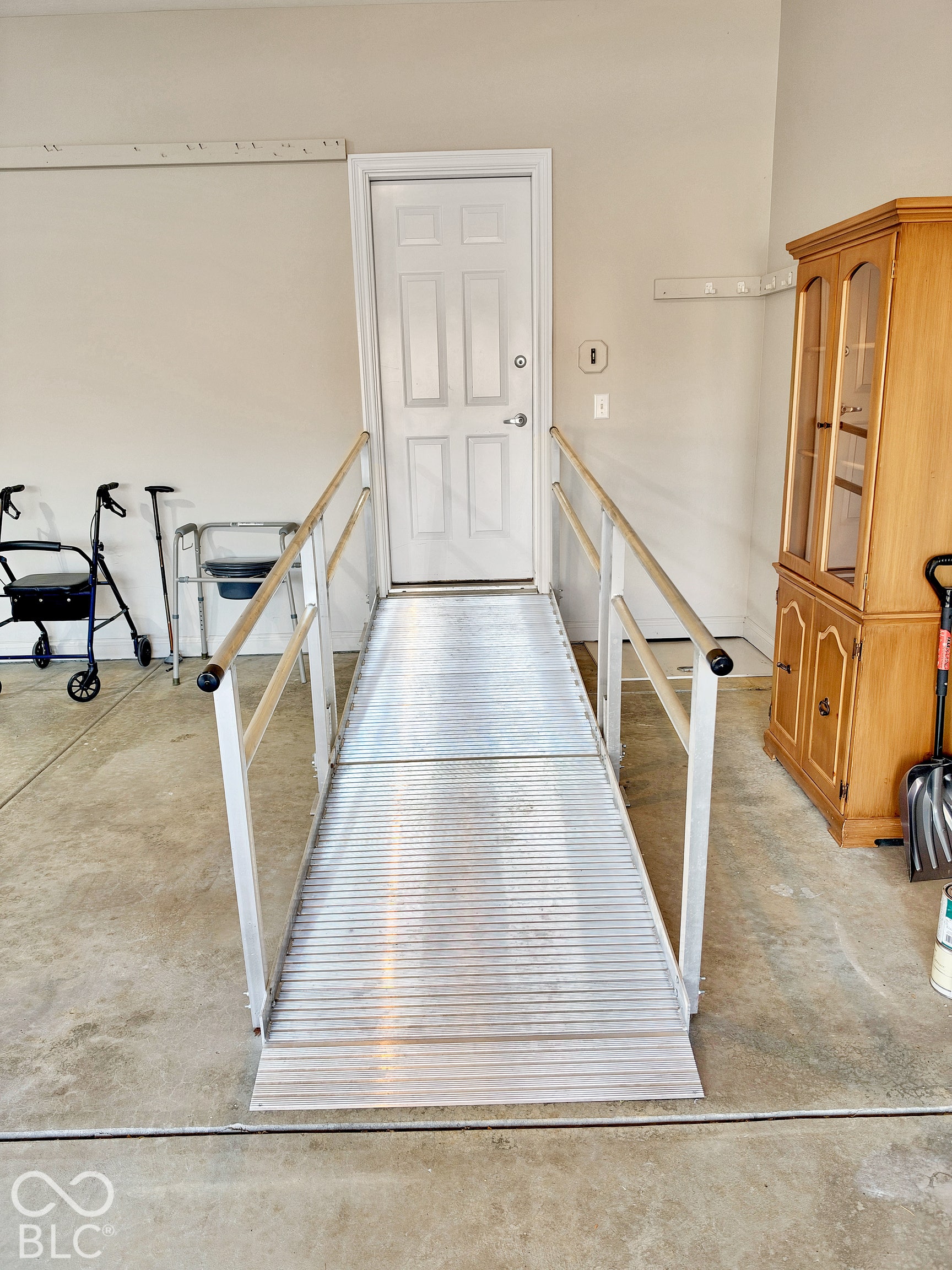 Interior access ramp with handrails in the garage leading to a  door to the kitchen.