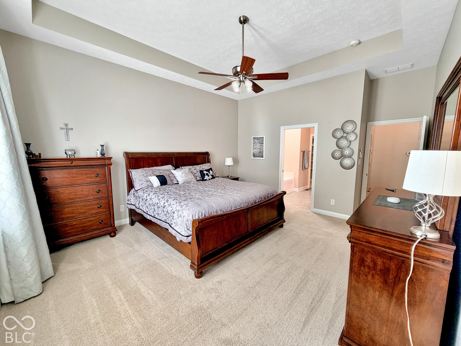 Tray ceiling with a ceiling fan, light-toned carpeting, and neutral wall paint