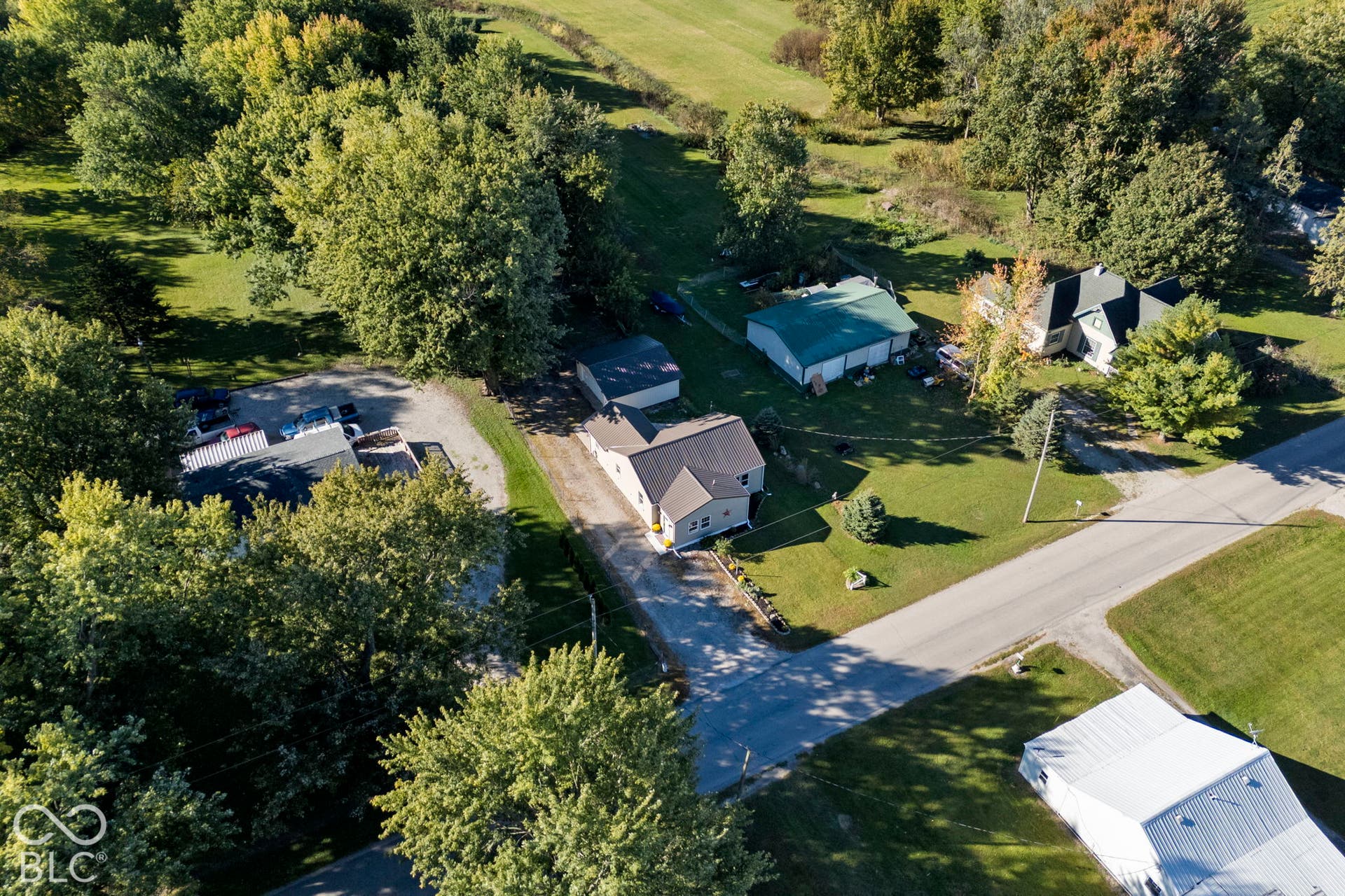 Property with a detached garage and additional outbuilding, surrounded by mature trees and green spaces