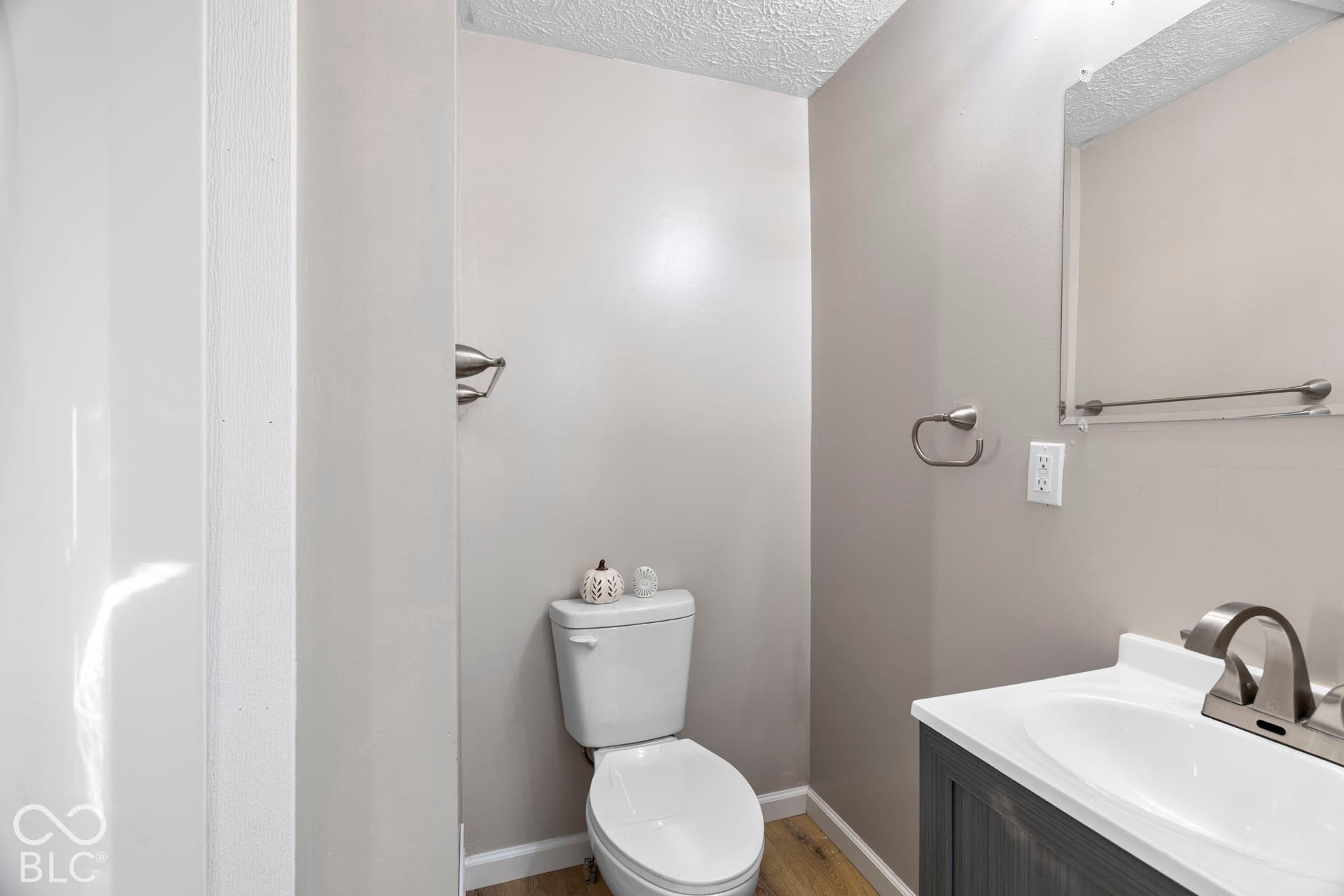 Bathroom featuring a vanity with an integrated sink, brushed nickel faucet, wall-mounted mirror, and wood-finish flooring