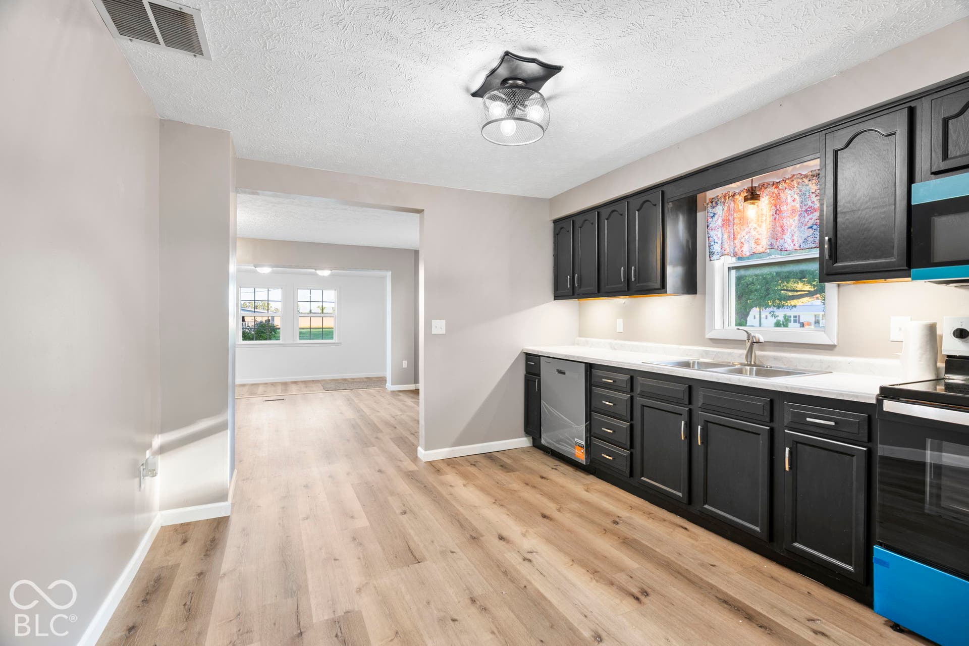 Kitchen featuring dark wood cabinetry, light-toned countertops, a double basin sink, and wood-finish flooring