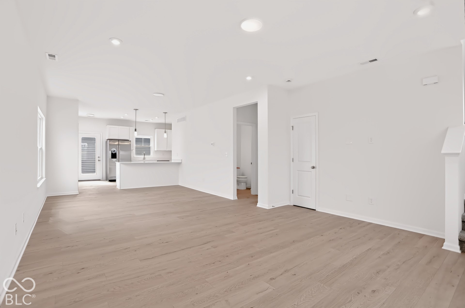 Open-concept living area featuring wood-finish flooring, recessed lighting, and white walls