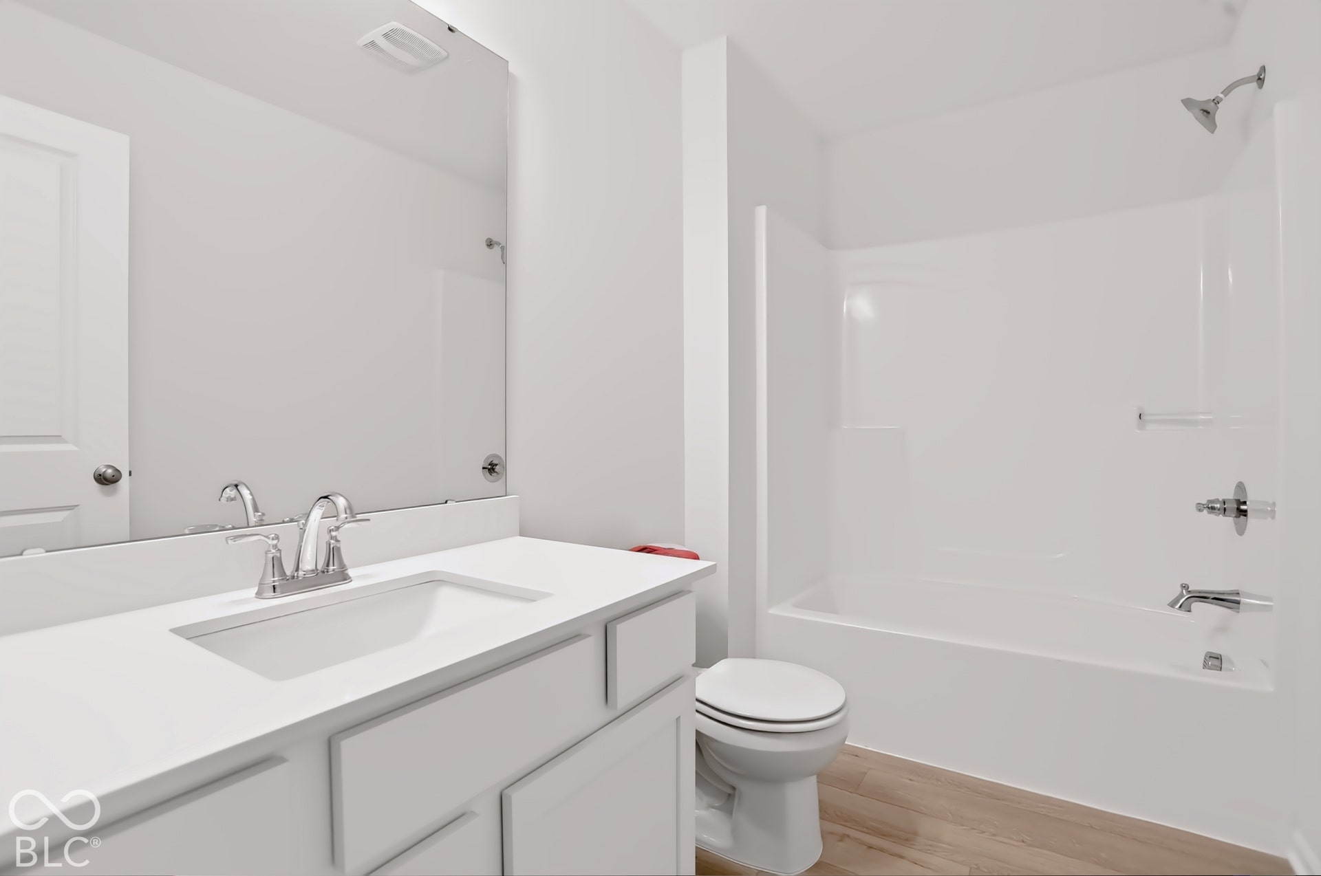 White vanity with integrated sink, chrome faucet, and expansive mirror