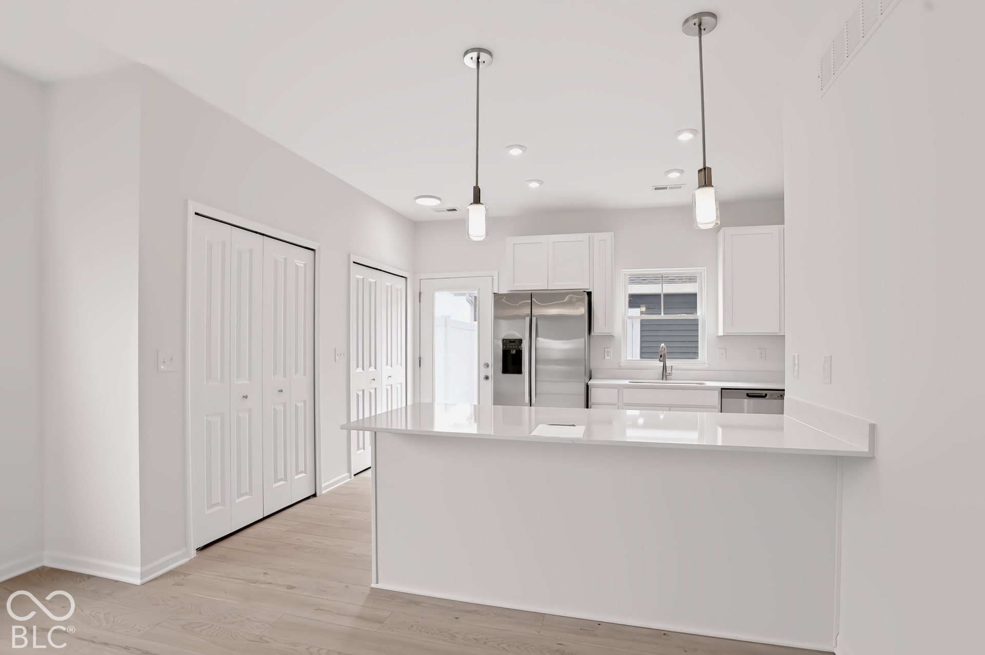 Kitchen featuring white shaker cabinetry, stainless steel appliances, a white subway tile backsplash, and a breakfast bar with a white countertop