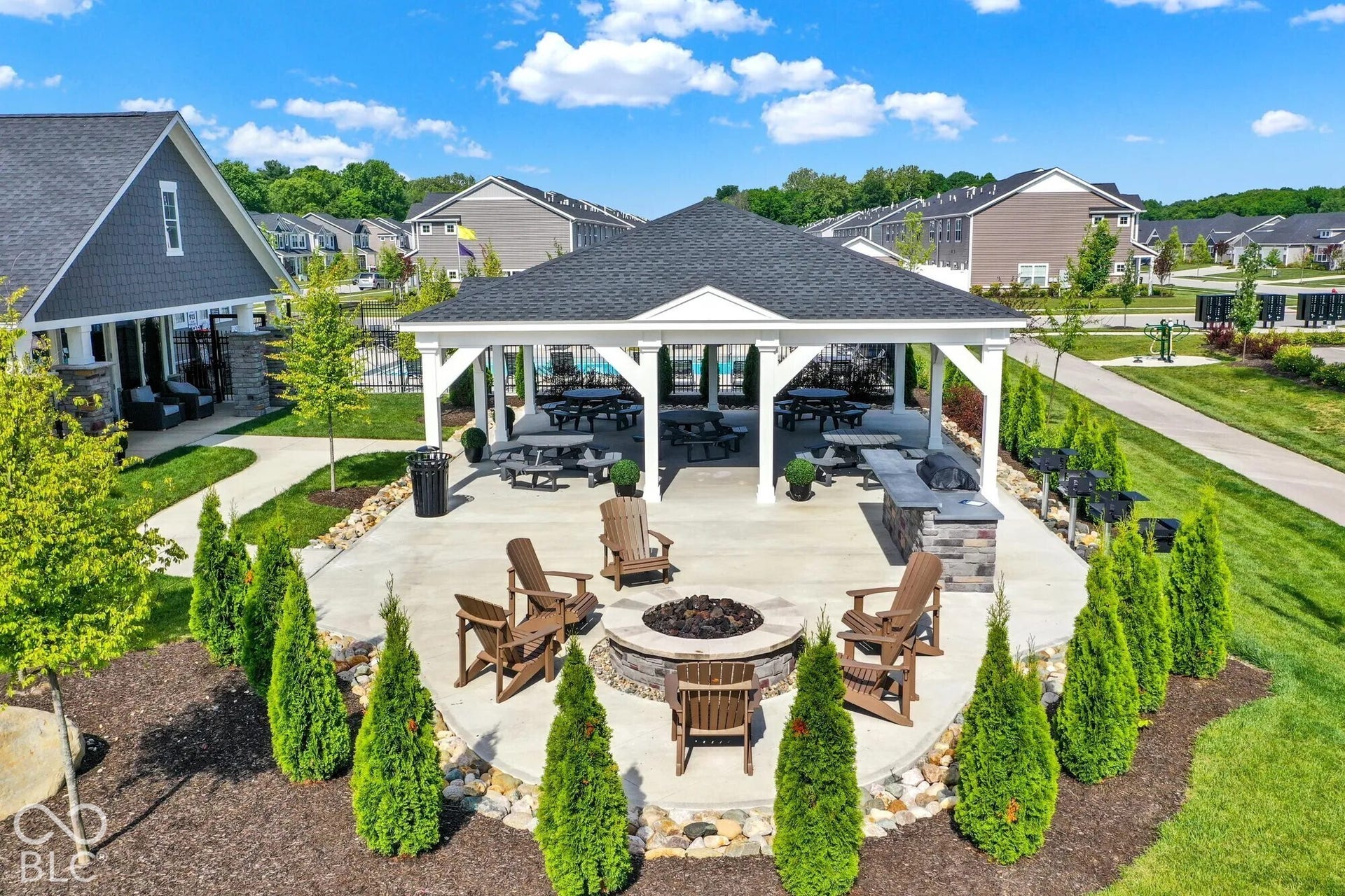 Covered outdoor patio featuring a central fire pit, built-in stone grill station, and paved walkways