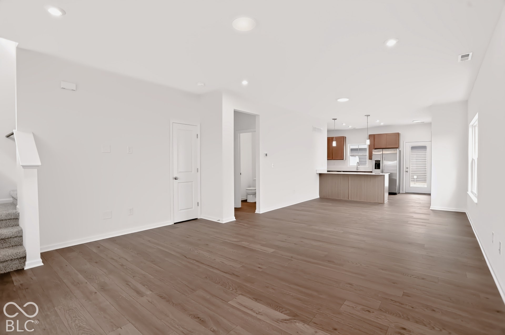 Open-concept interior featuring wood-finish flooring, recessed lighting, and a modern kitchen with a large island