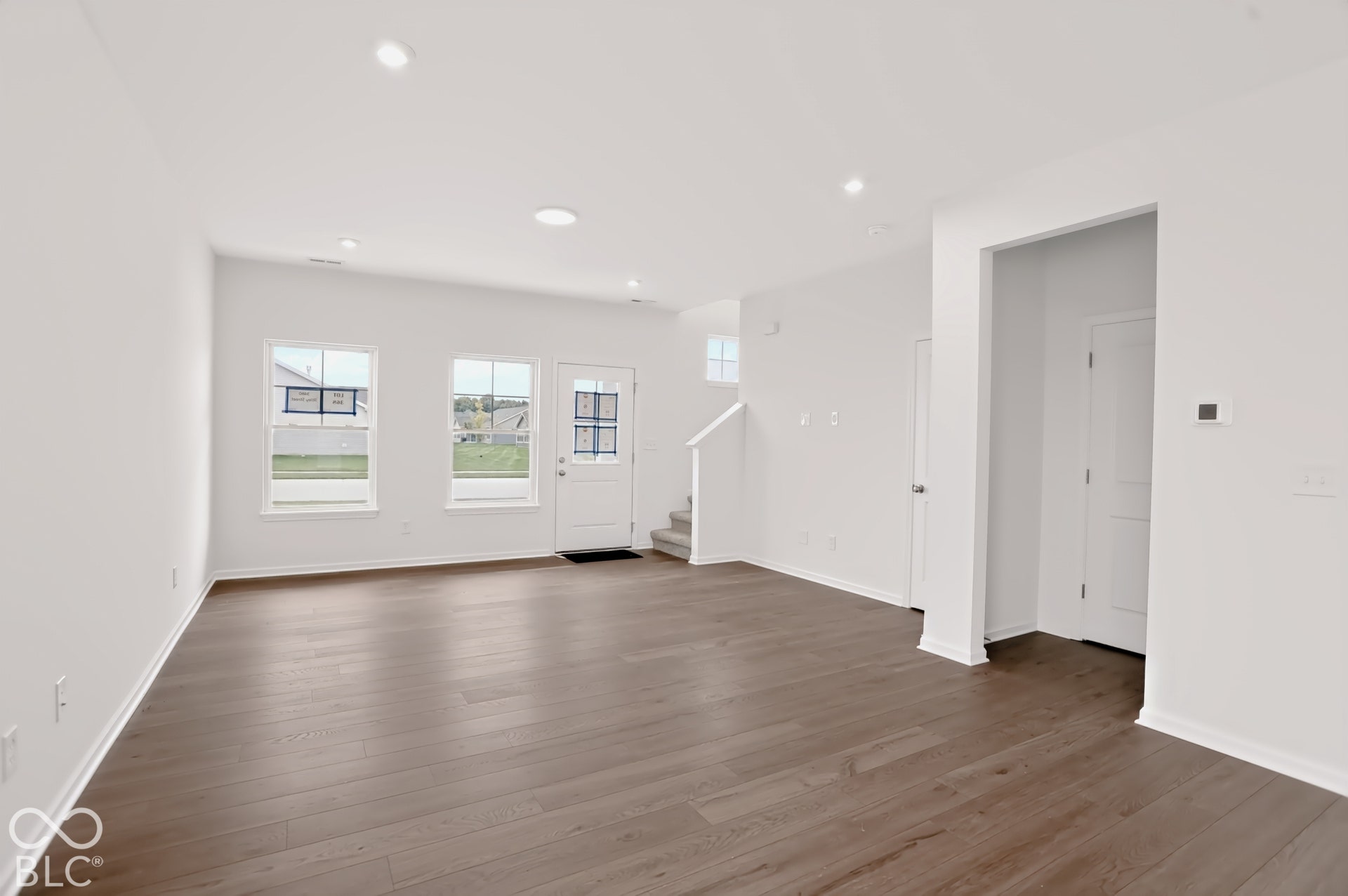 Expansive open-concept living area featuring recessed lighting, wood-finish flooring, white walls, and multiple windows