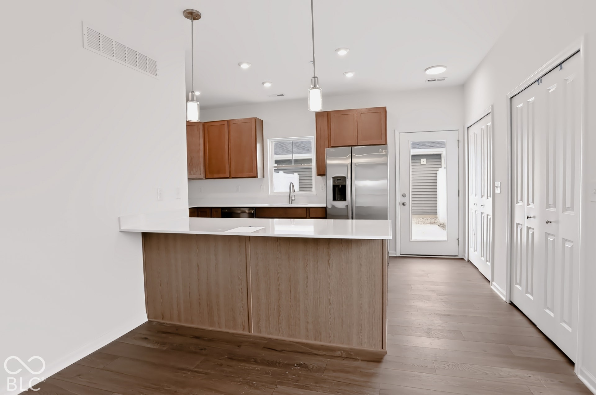 Kitchen featuring wood-finish flooring, stainless steel appliances, white countertops, and recessed lighting