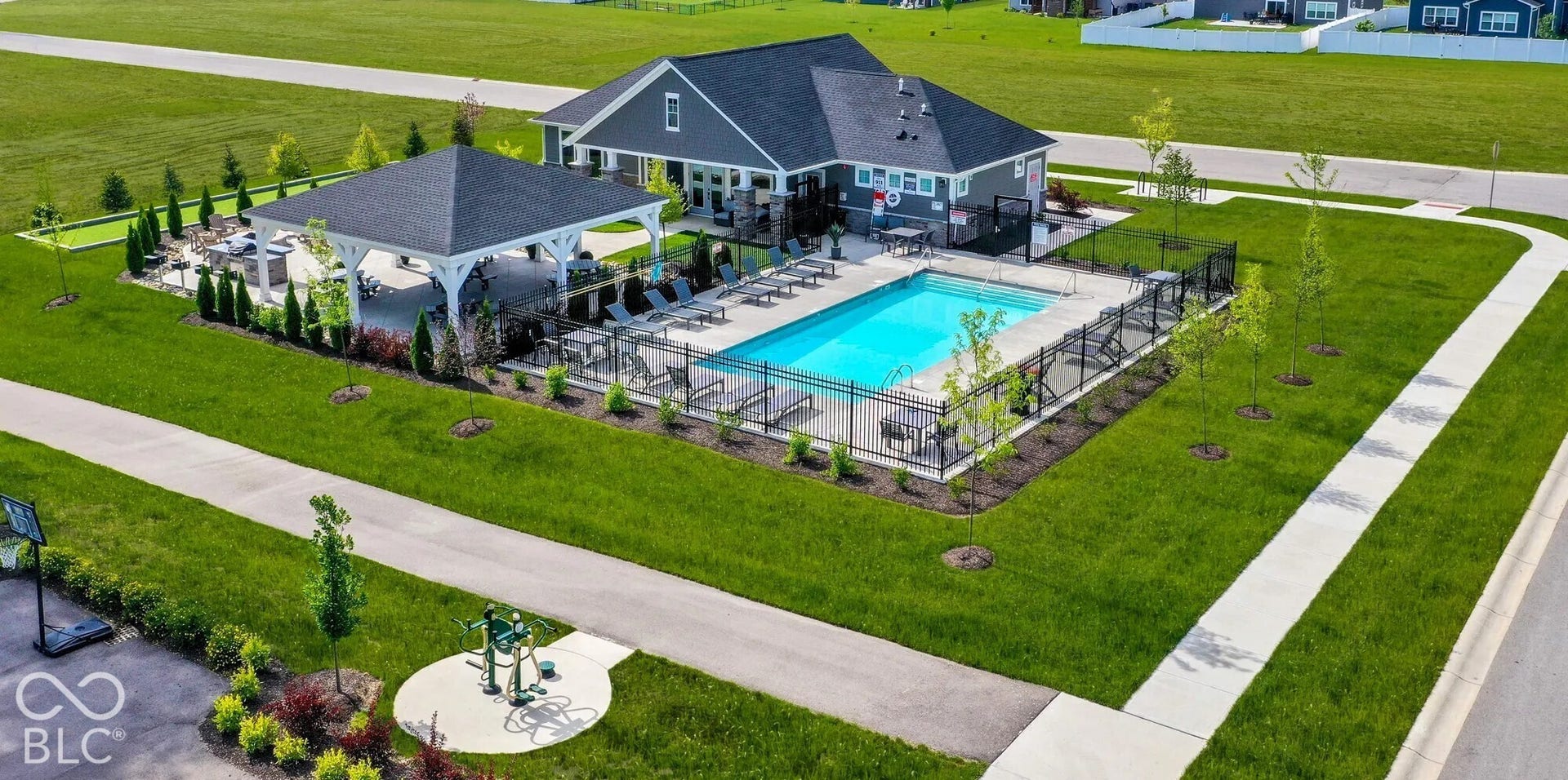 Outdoor swimming pool with surrounding fencing, adjacent shaded pergola, and nearby fitness equipment