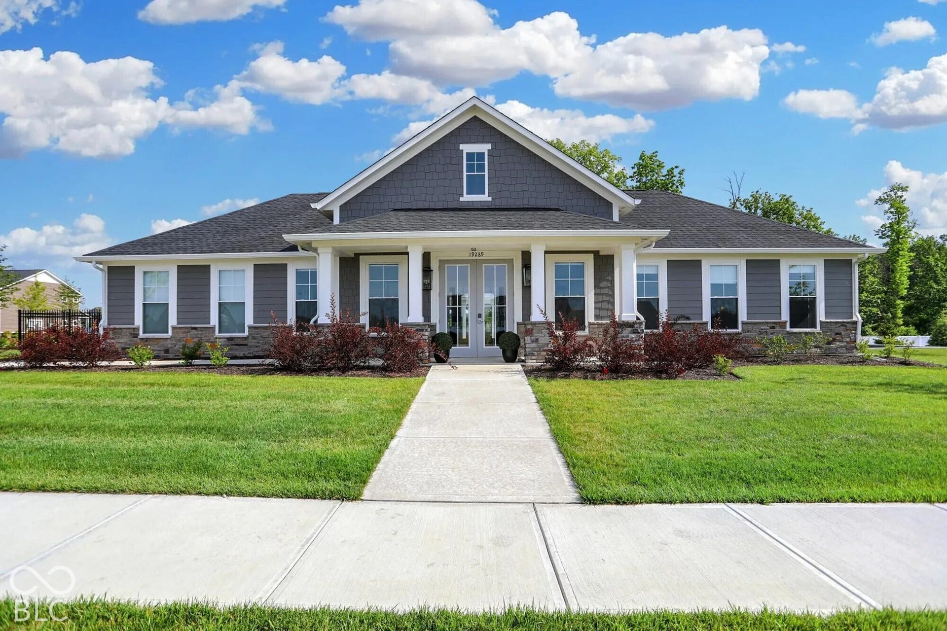 Contemporary ranch-style residence with an attached portico, featuring gray horizontal siding, natural stone veneer accents, and white window trim