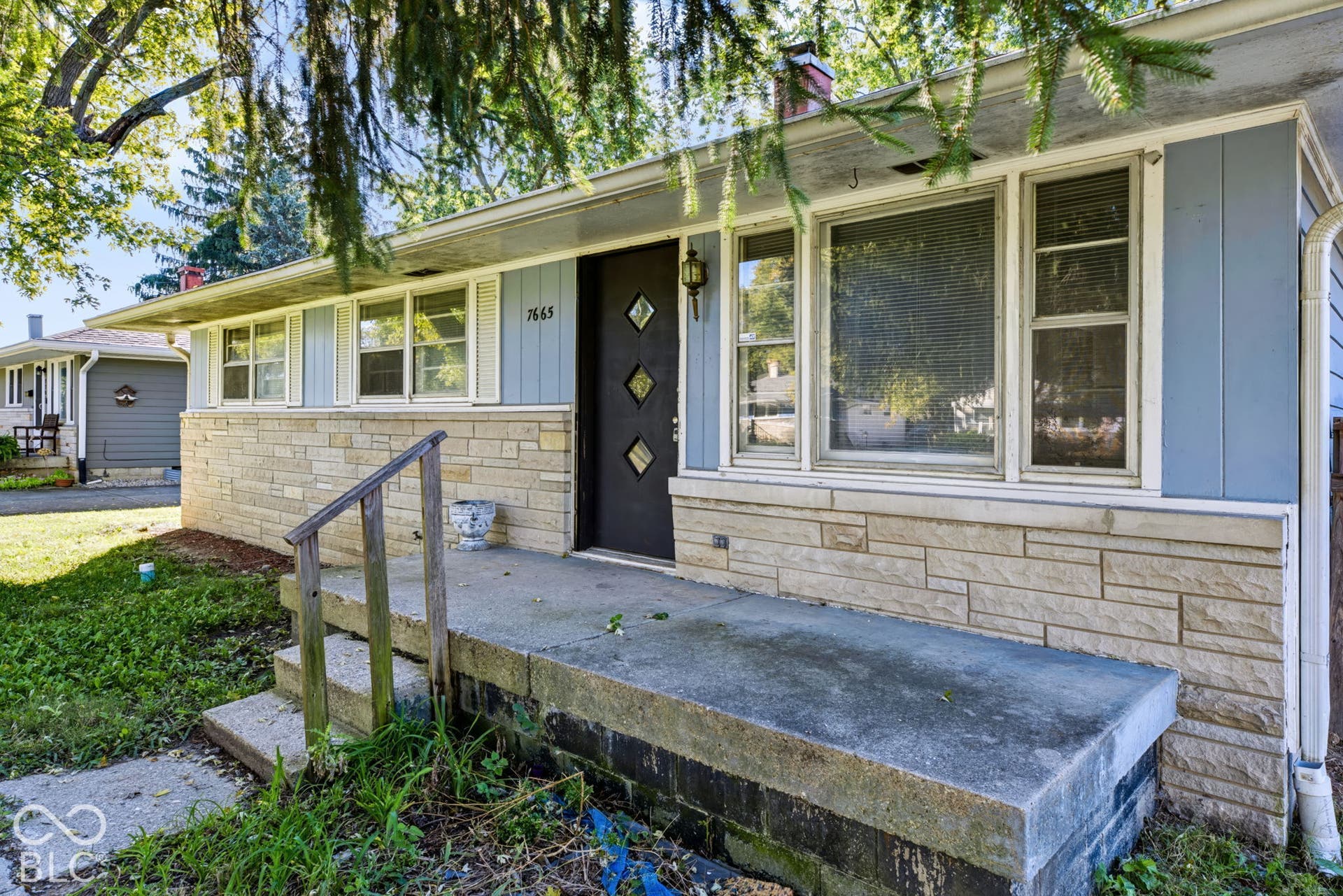 Siding exterior with stone veneer accents, multiple window units, and a covered front porch featuring a concrete surface
