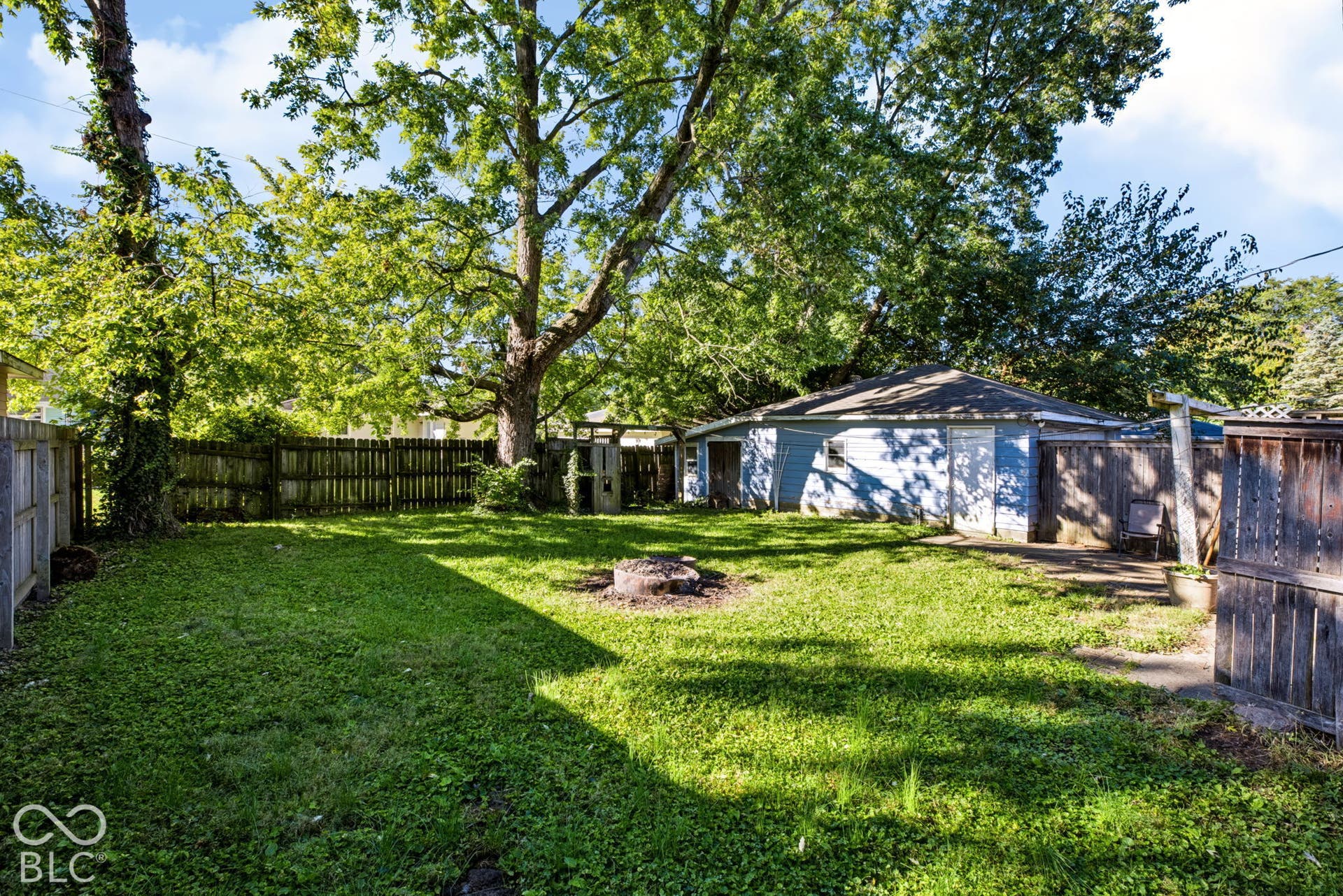 Expansive grassy yard with mature trees and perimeter fencing