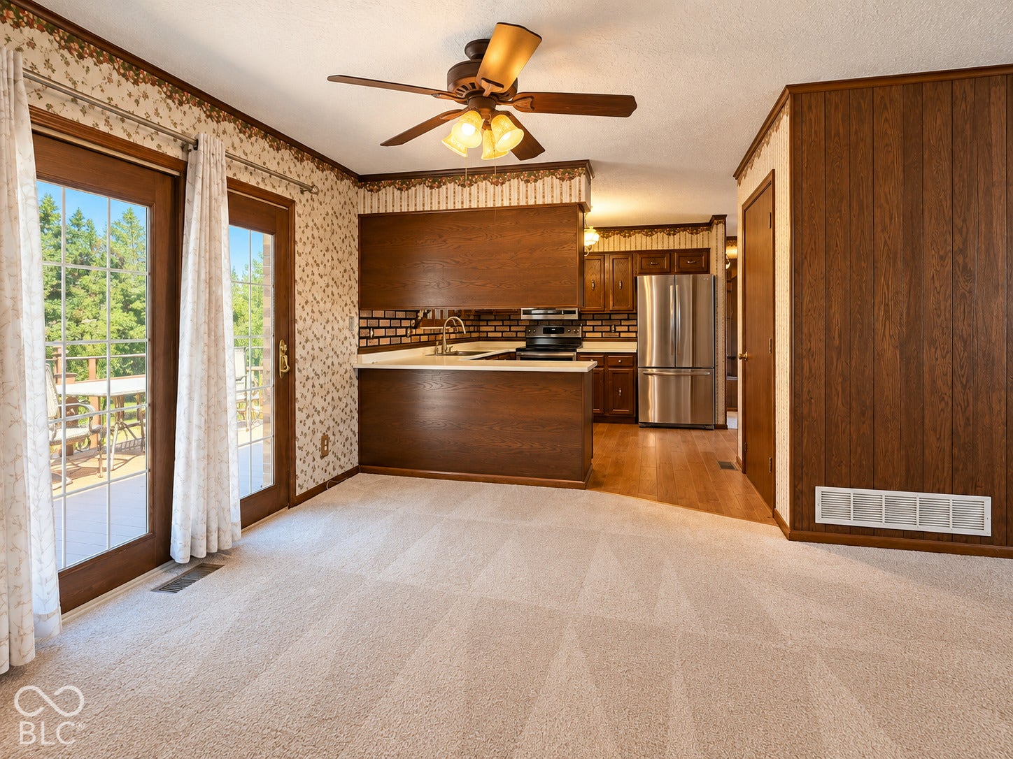 3680 S State Road 75, Coatesville, IN 46121 French doors opening to an exterior deck, carpeted flooring, wood-paneled walls, and a ceiling fan with integrated lighting