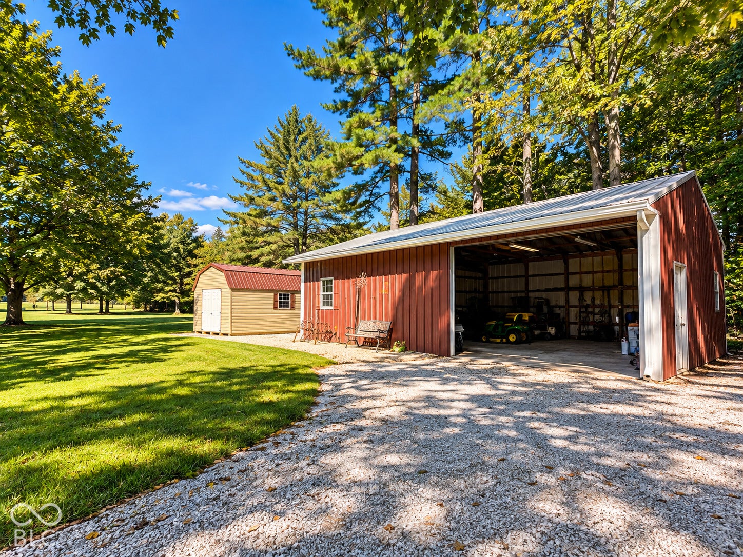 3680 S State Road 75, Coatesville, IN 46121 Expansive gravel driveway leading to a large open-sided barn with a metal roof and a separate storage shed