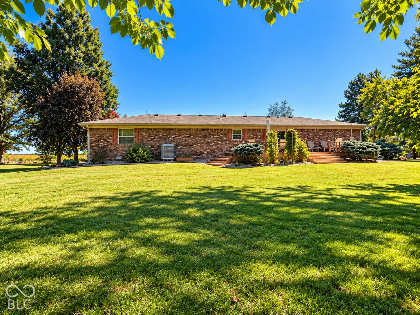 3680 S State Road 75, Coatesville, IN 46121 Expansive green lawn with mature trees, brick exterior, and a multi-level wood deck