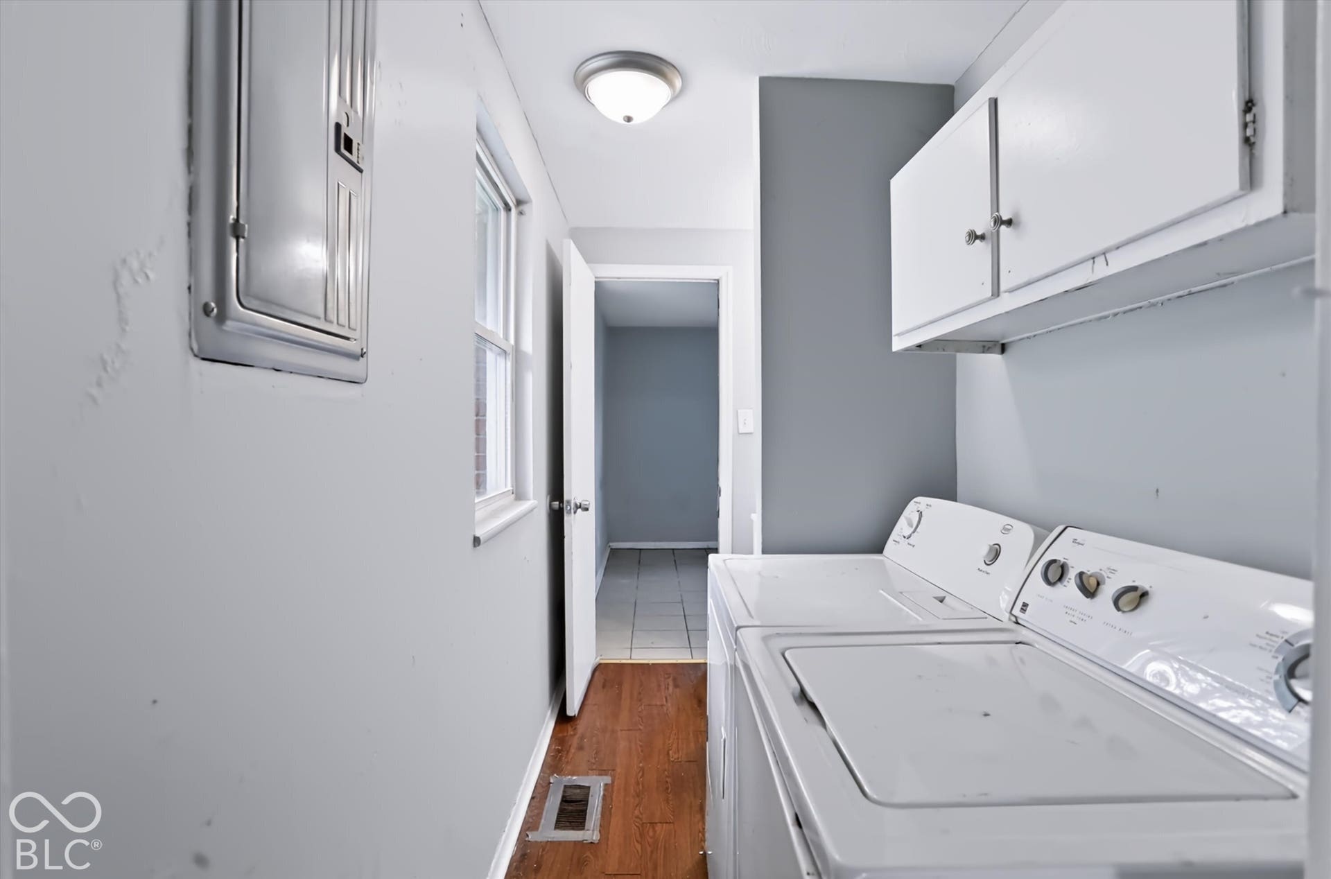 Laundry area featuring wood-finish flooring, a window, and built-in upper cabinetry