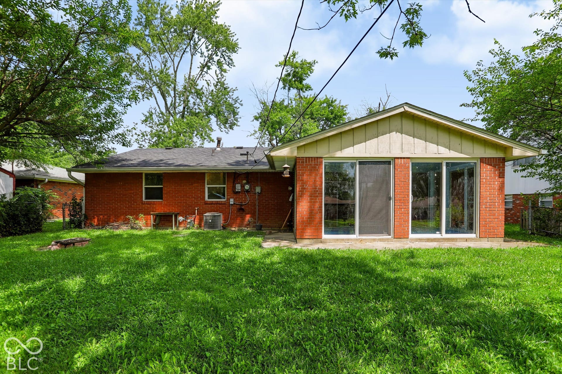 Red brick exterior with multiple sliding glass doors, a gabled roof, and an expansive lawn