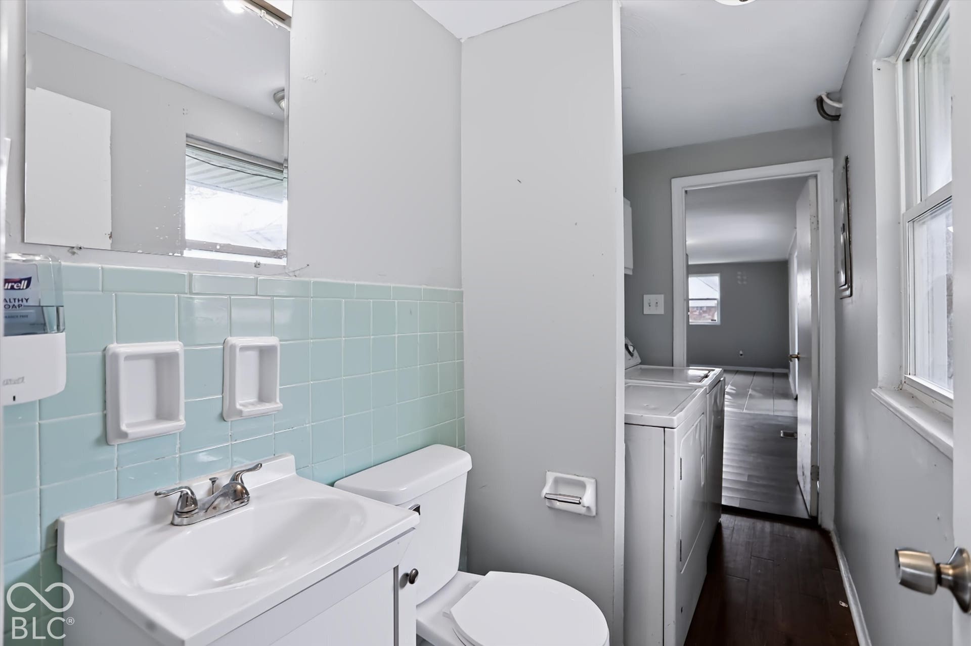 Bathroom featuring light blue wall tiling, a white vanity with an integrated sink, and a toilet