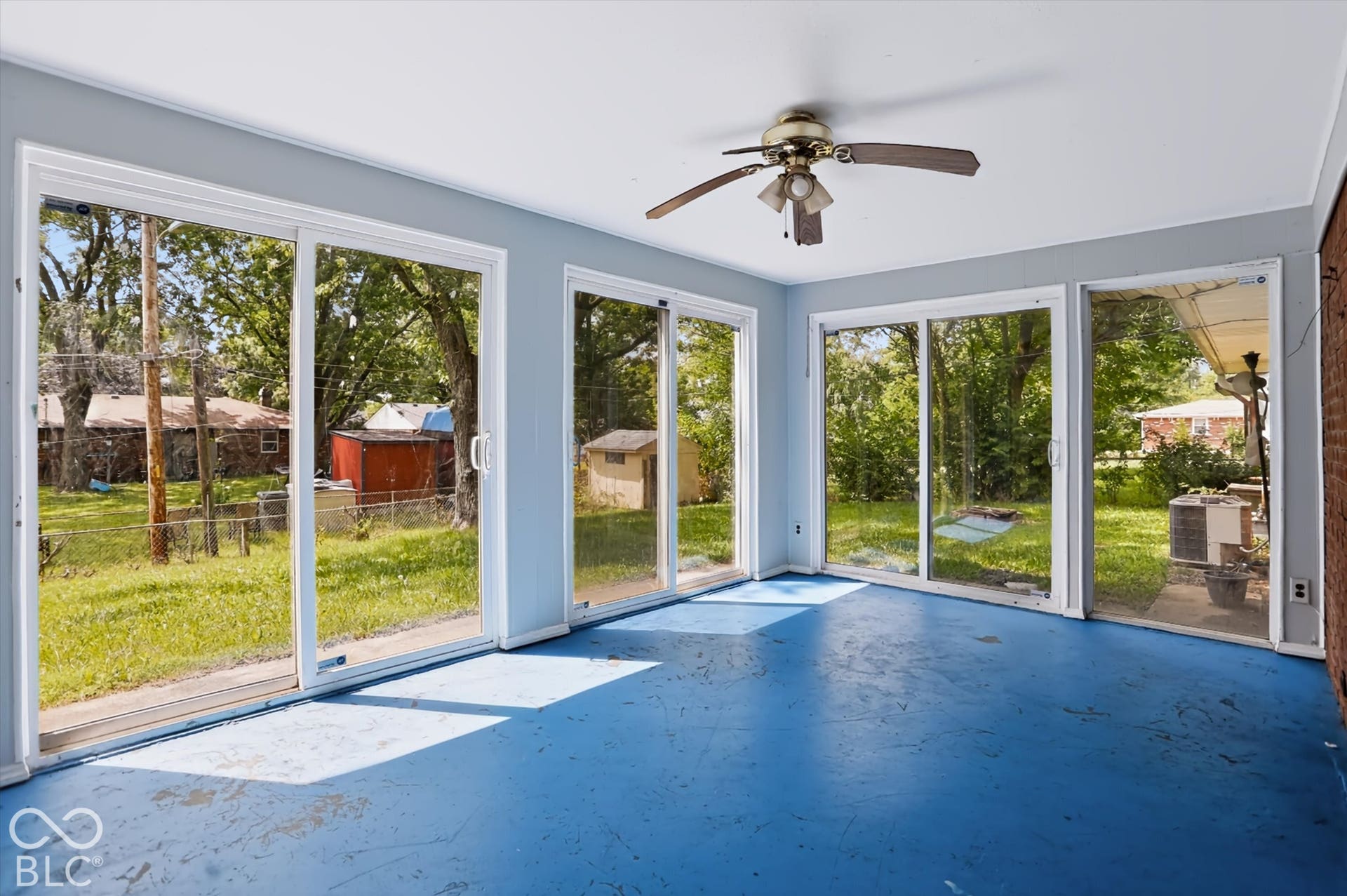 Multiple sliding glass doors, ceiling fan, and painted flooring