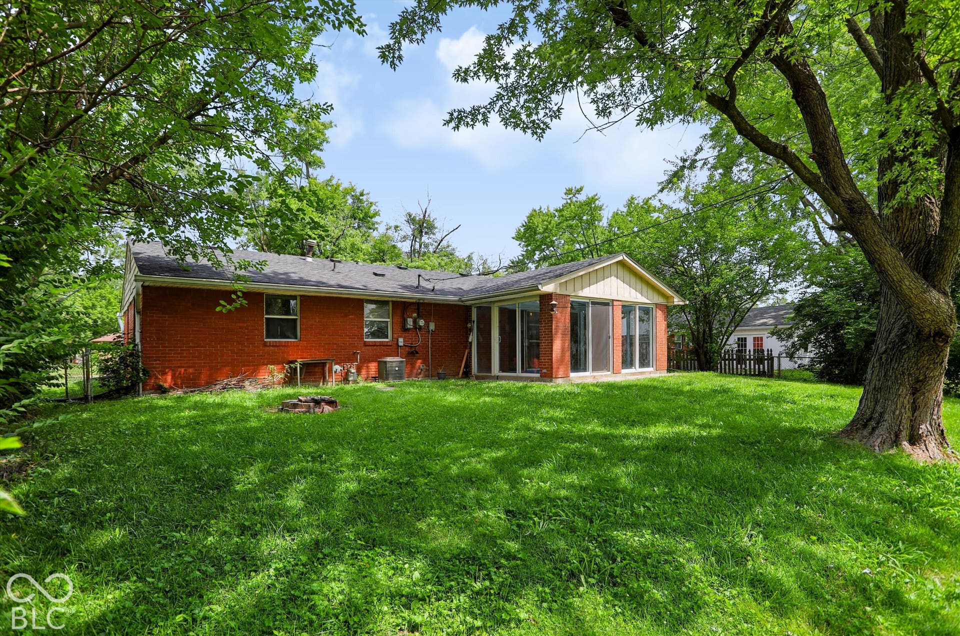 Expansive green lawn with mature trees and a brick-clad exterior