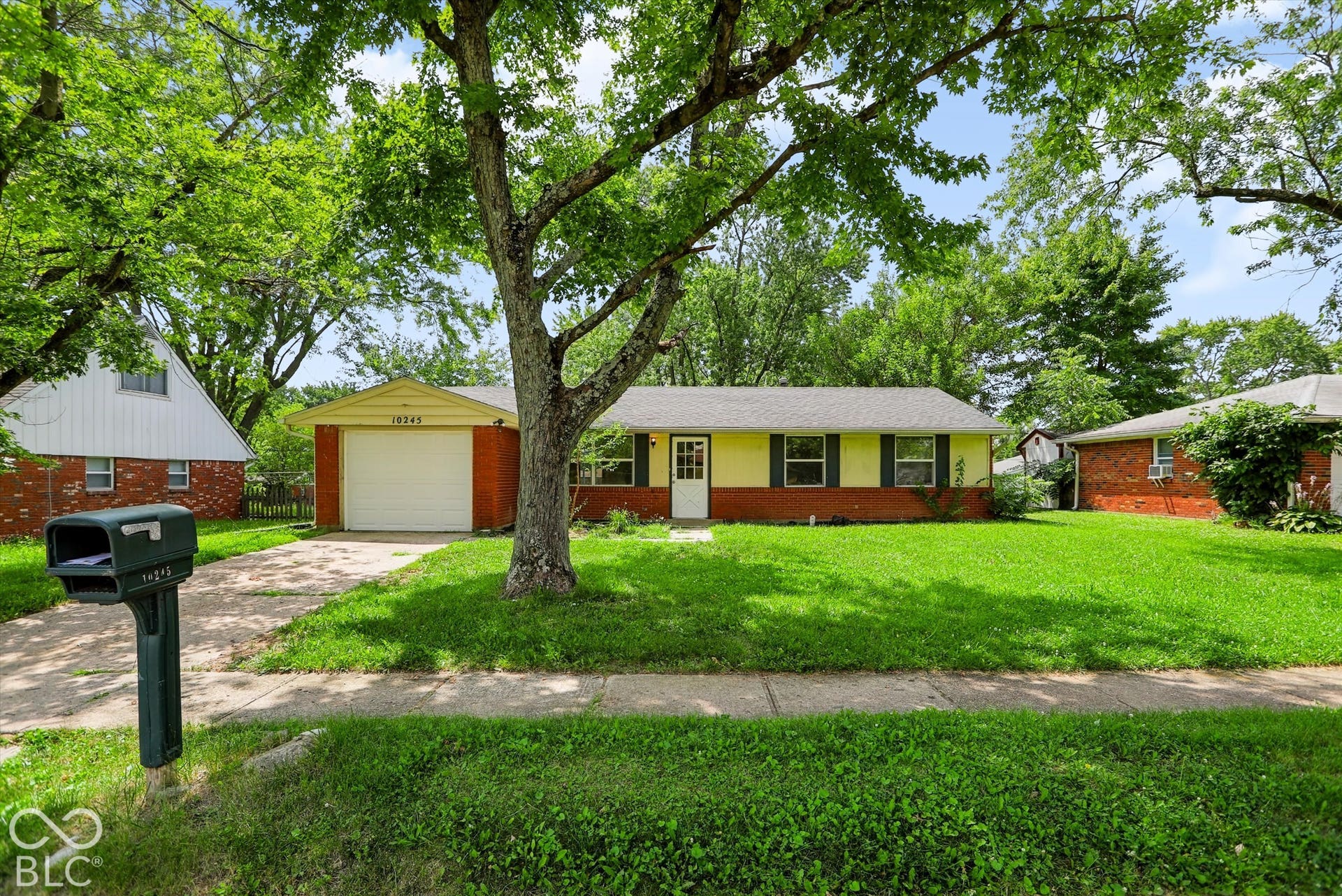 Ranch-style residence featuring a yellow facade with brick accents and a gray shingle roof