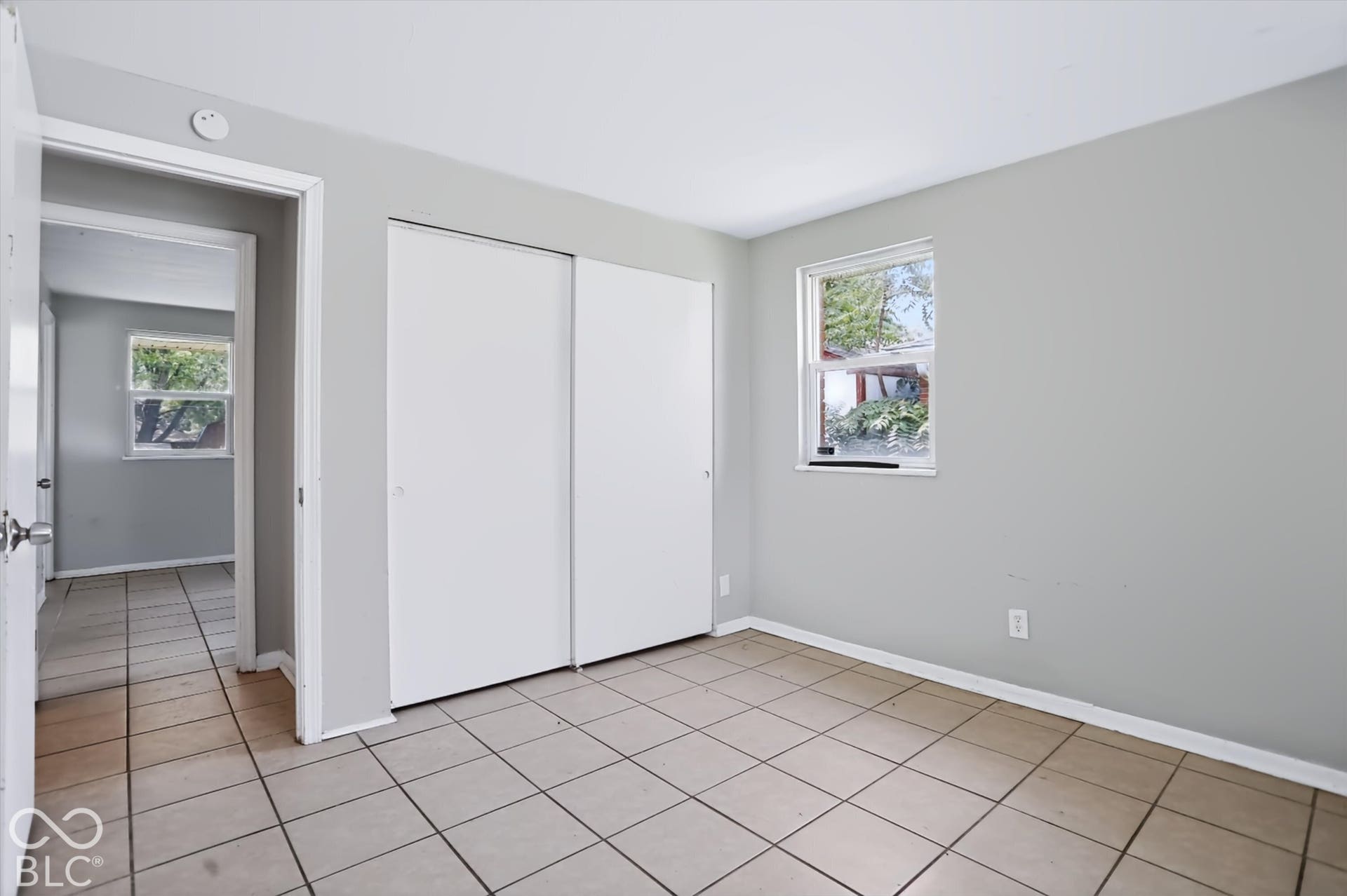 Neutral gray wall paint, tile flooring, white sliding closet doors, and white trim