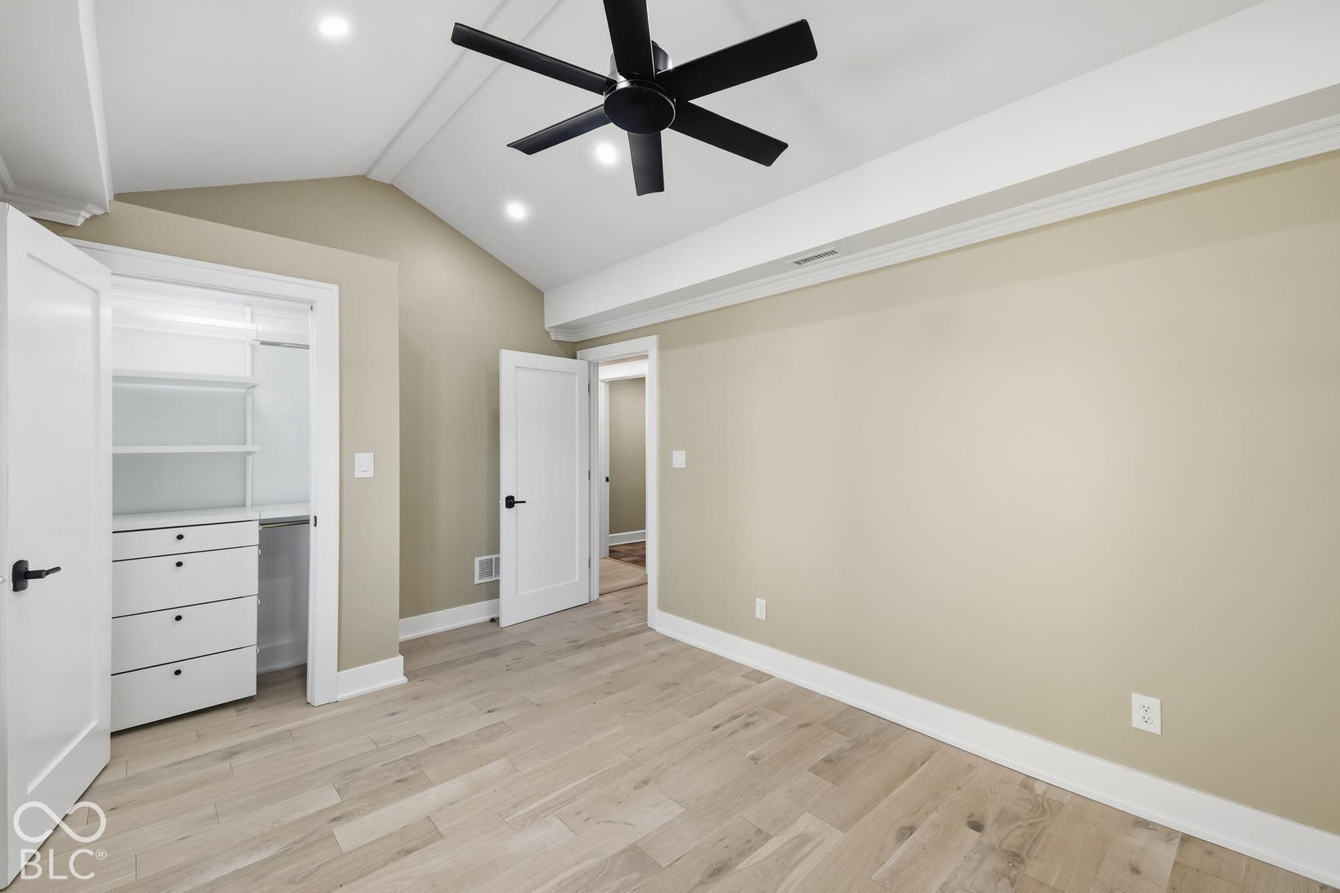 Vaulted ceiling with recessed lighting and a ceiling fan, light wood-finish flooring, custom closet system with shelving and drawers, and white trim